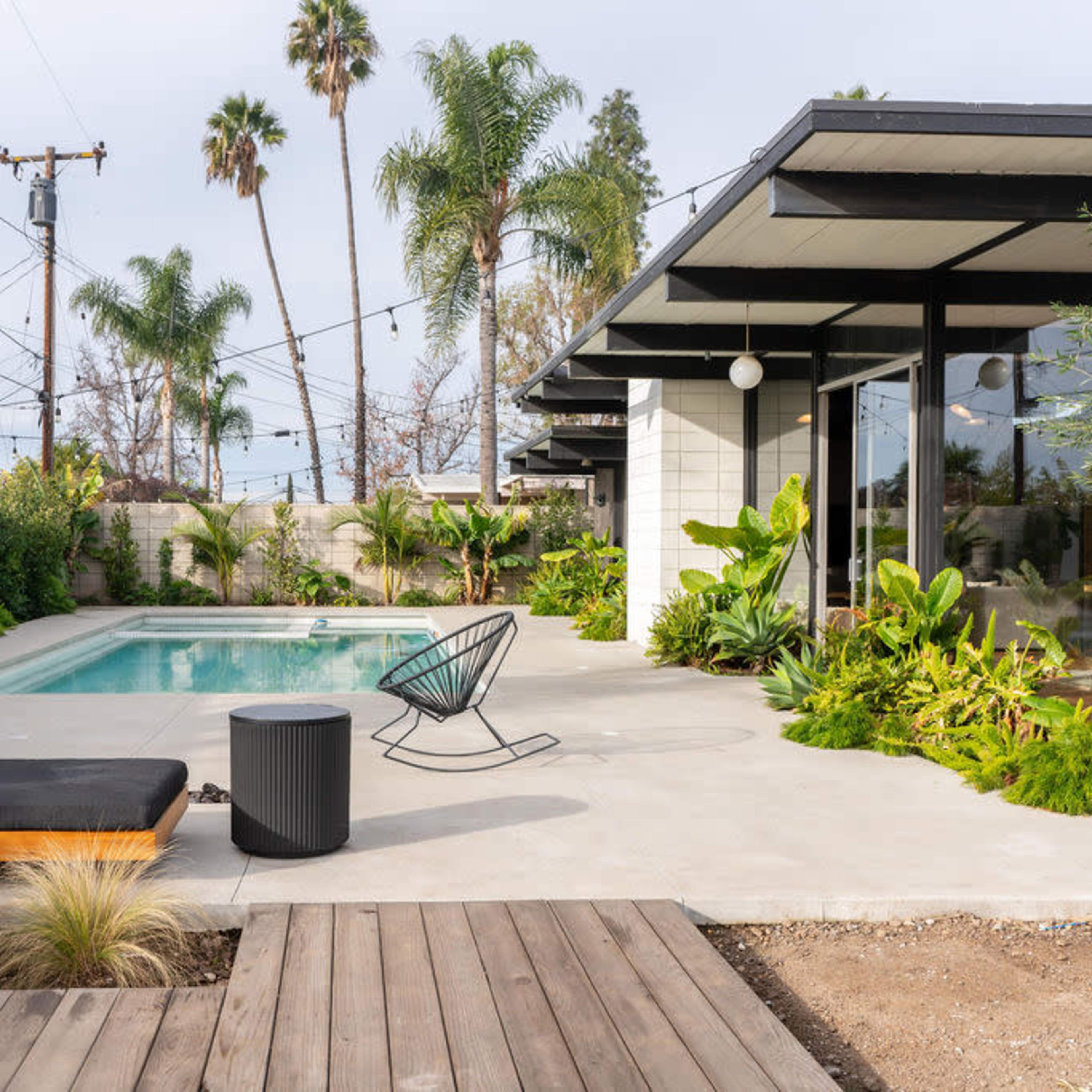 A modern home with a swimming pool surrounded by lush greenery and outdoor seating.