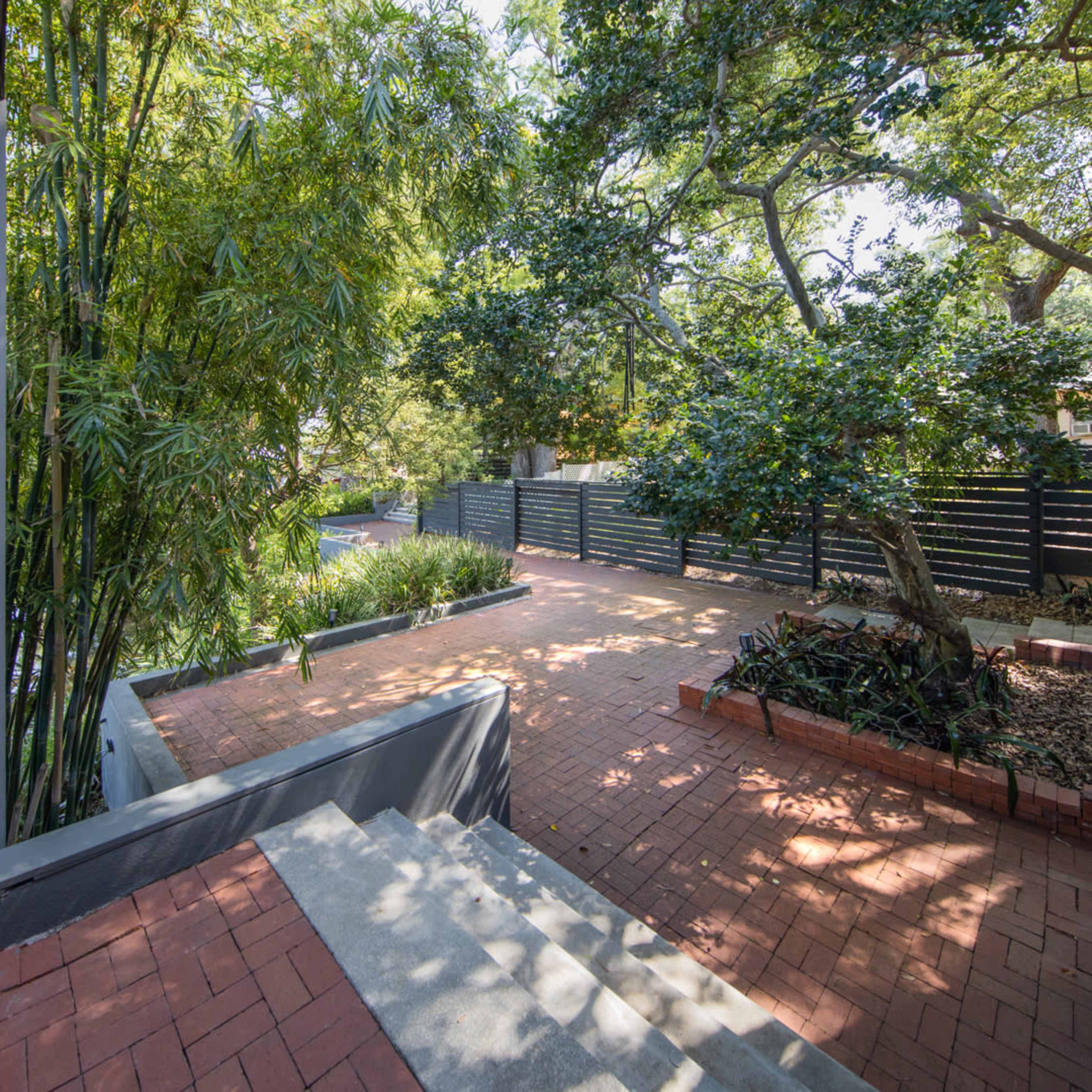 A brick pathway leads to a landscaped outdoor area surrounded by trees and greenery.