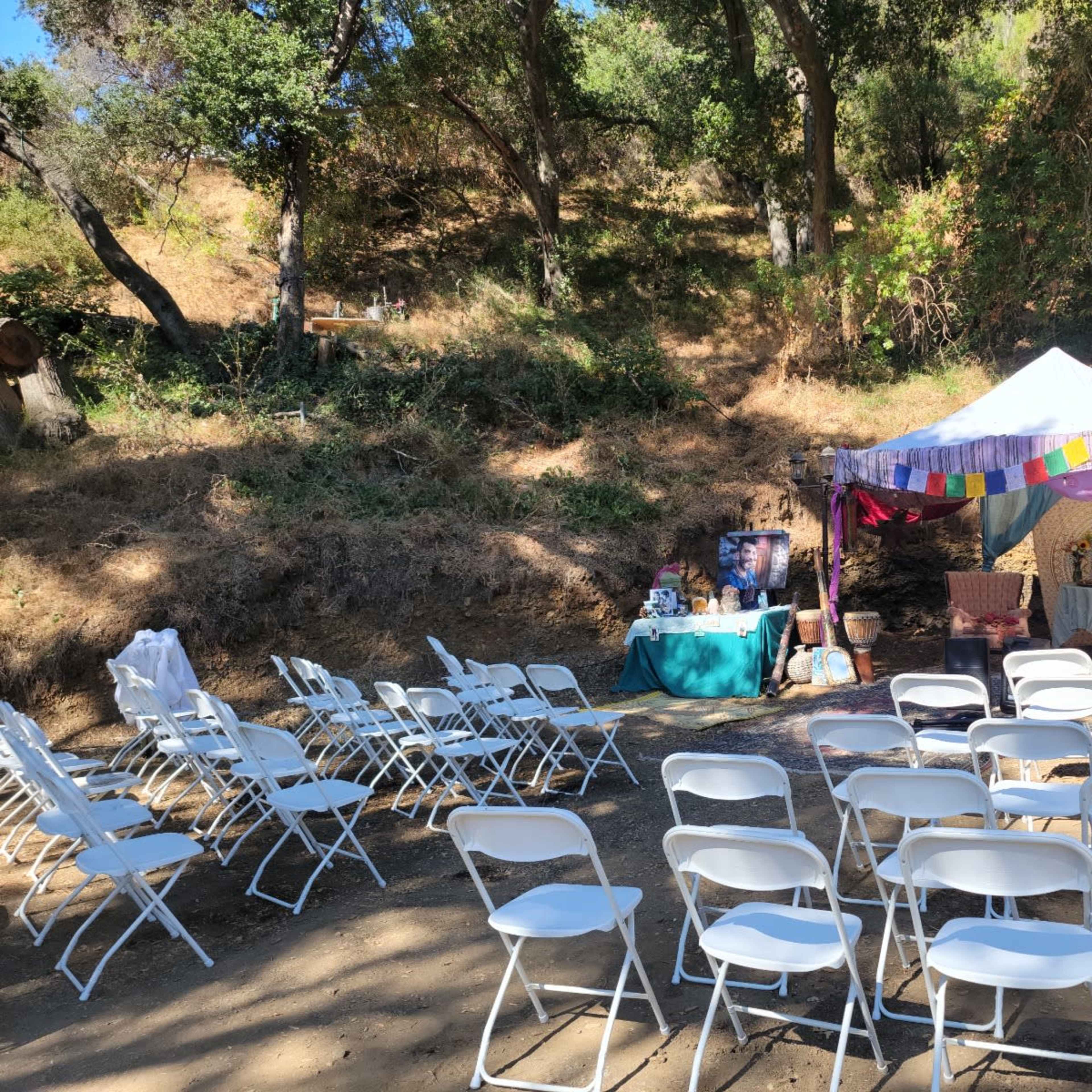 A setup for an outdoor event features a white tent with colorful decorations and seating arranged in rows.