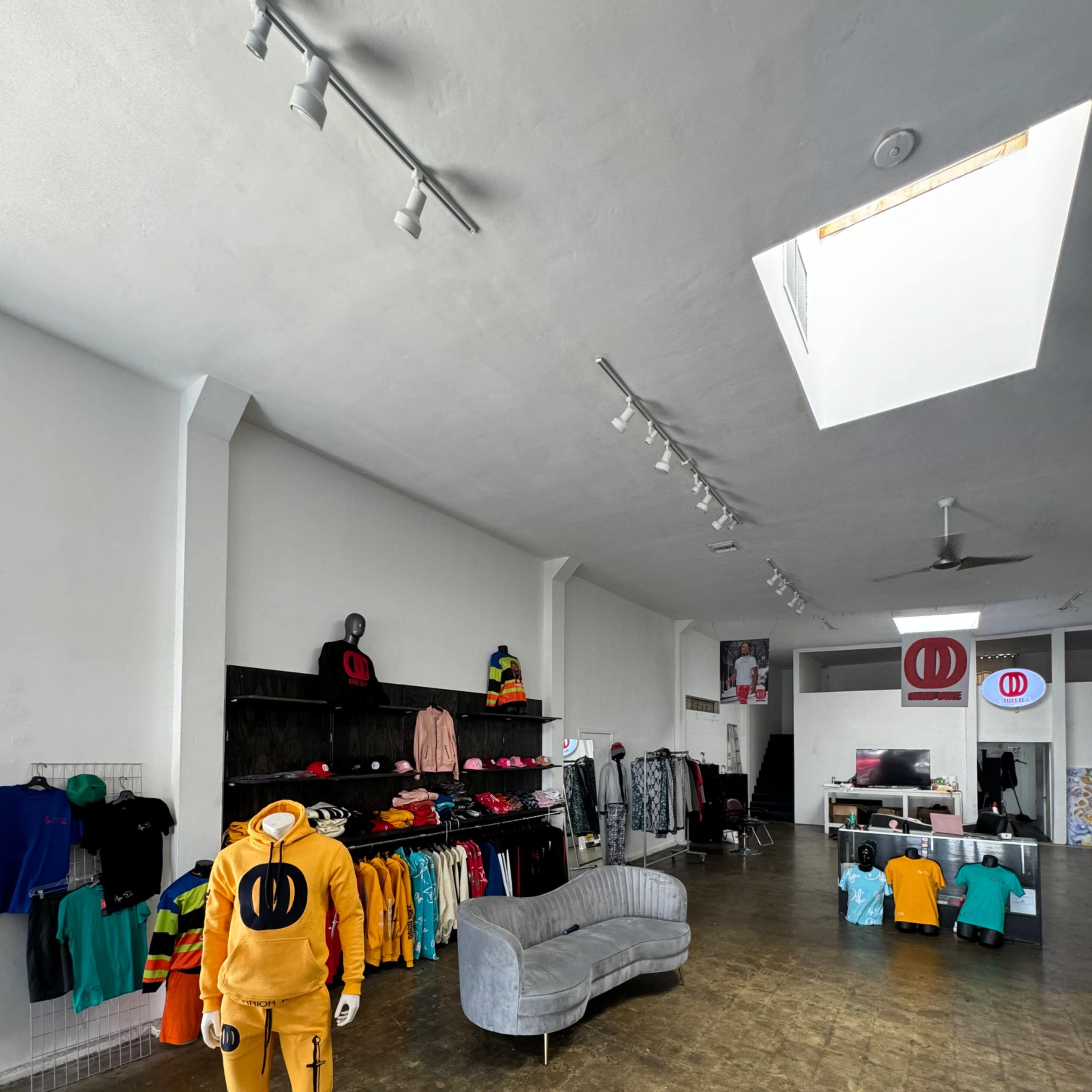 An apparel store with a gray couch and various clothing items displayed on racks and hangers.