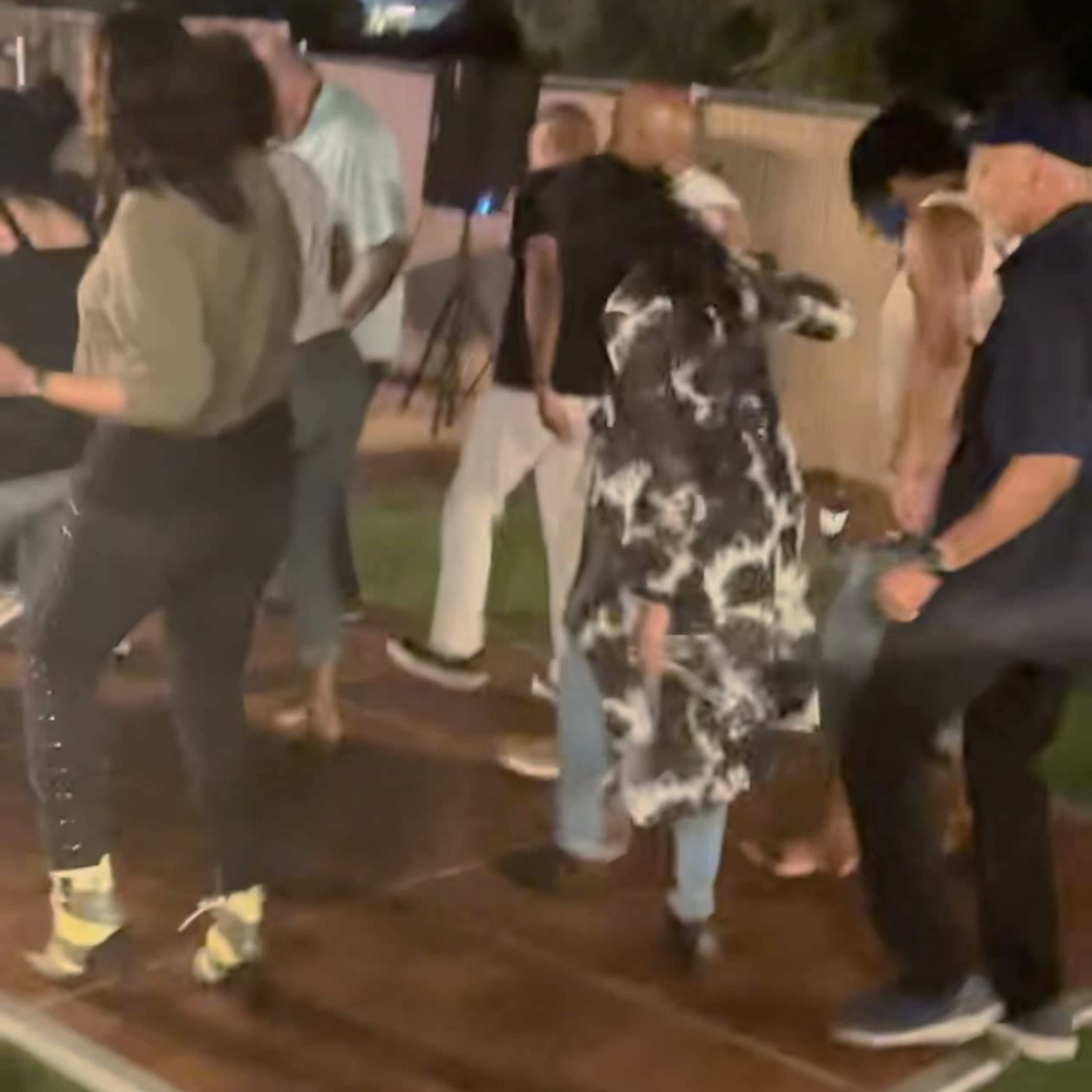 A group of people is dancing on a wooden dance floor at night in an outdoor setting.