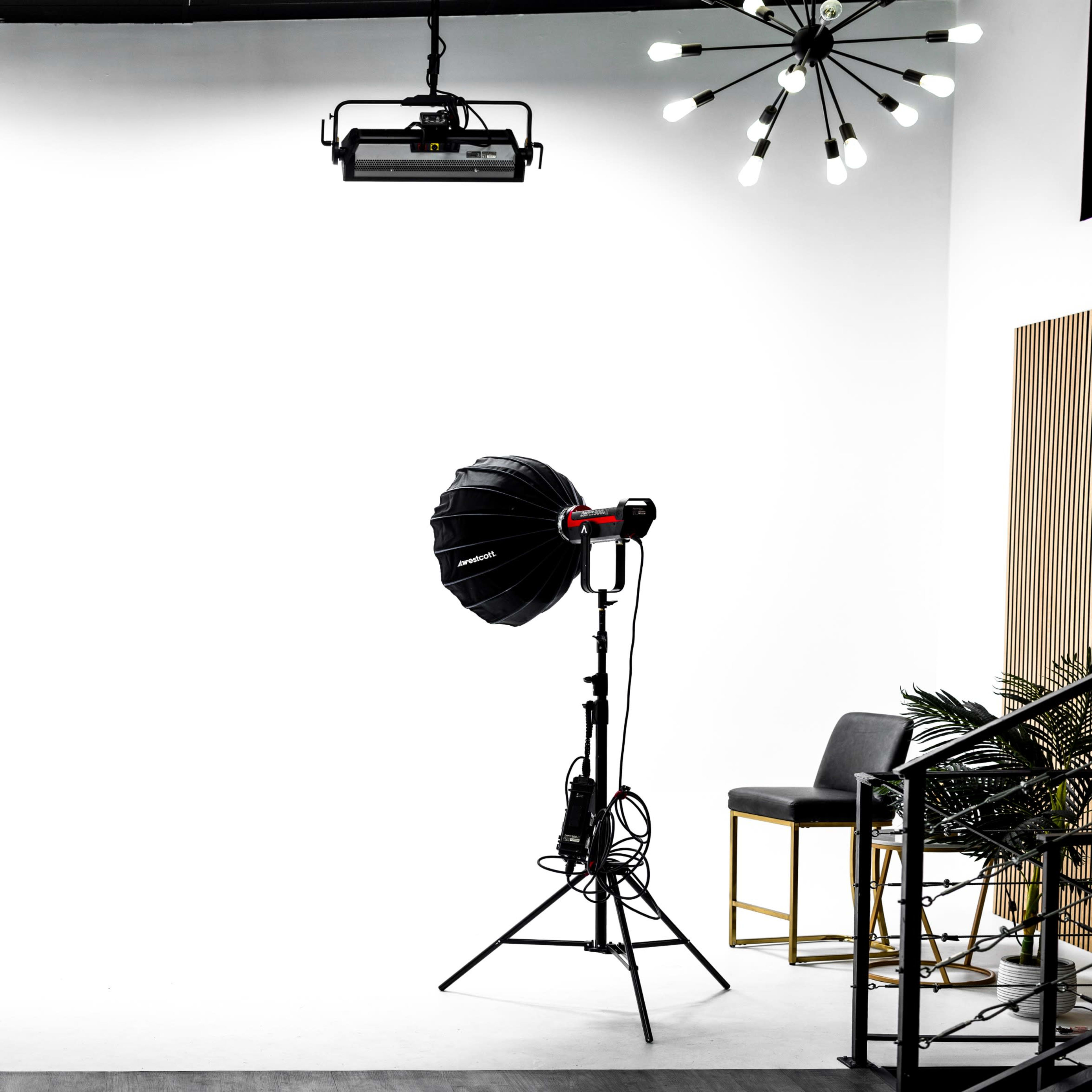 A photography studio with two large light fixtures on stands facing a blank white backdrop.