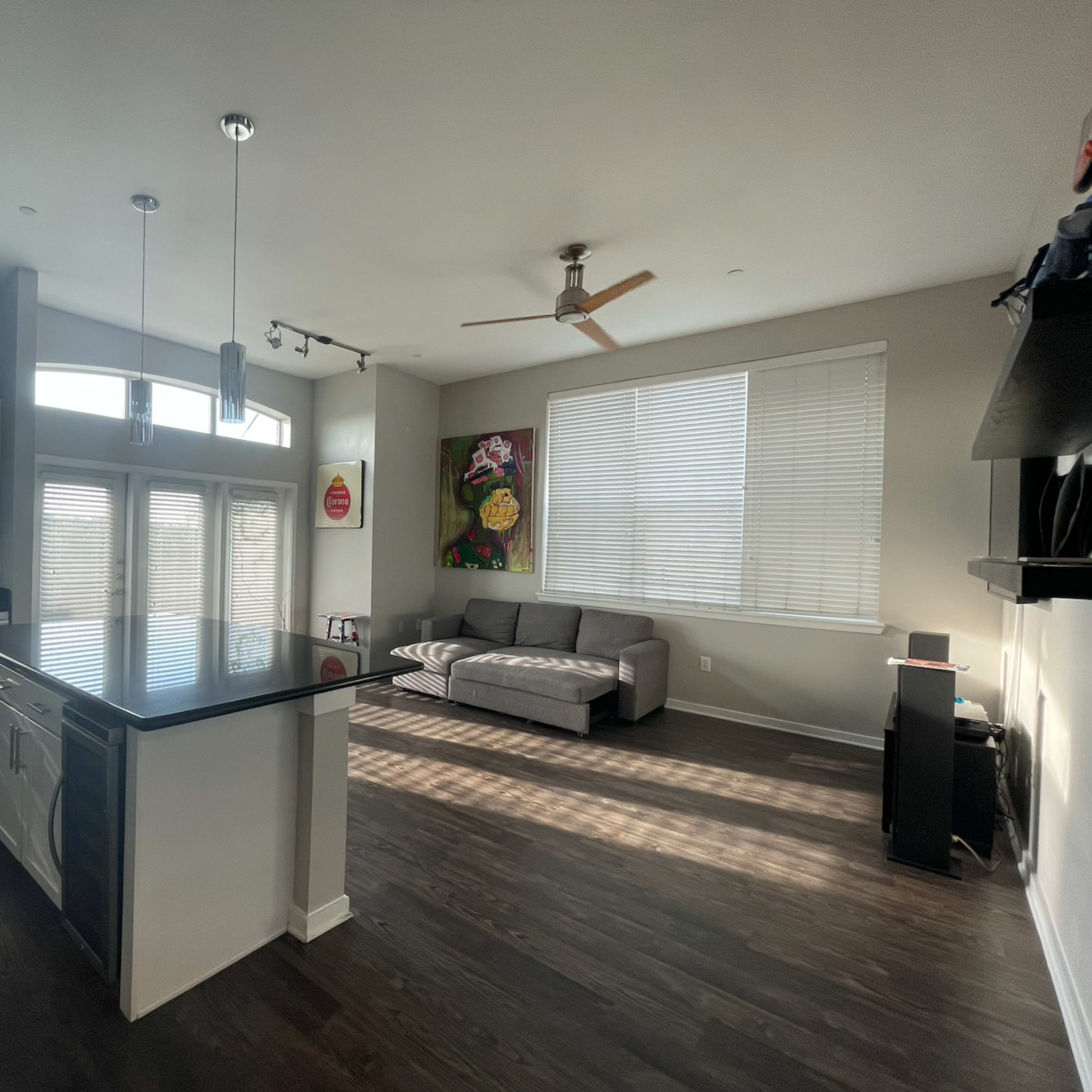 A modern kitchen and living room area with an island, large windows, and a gray couch.