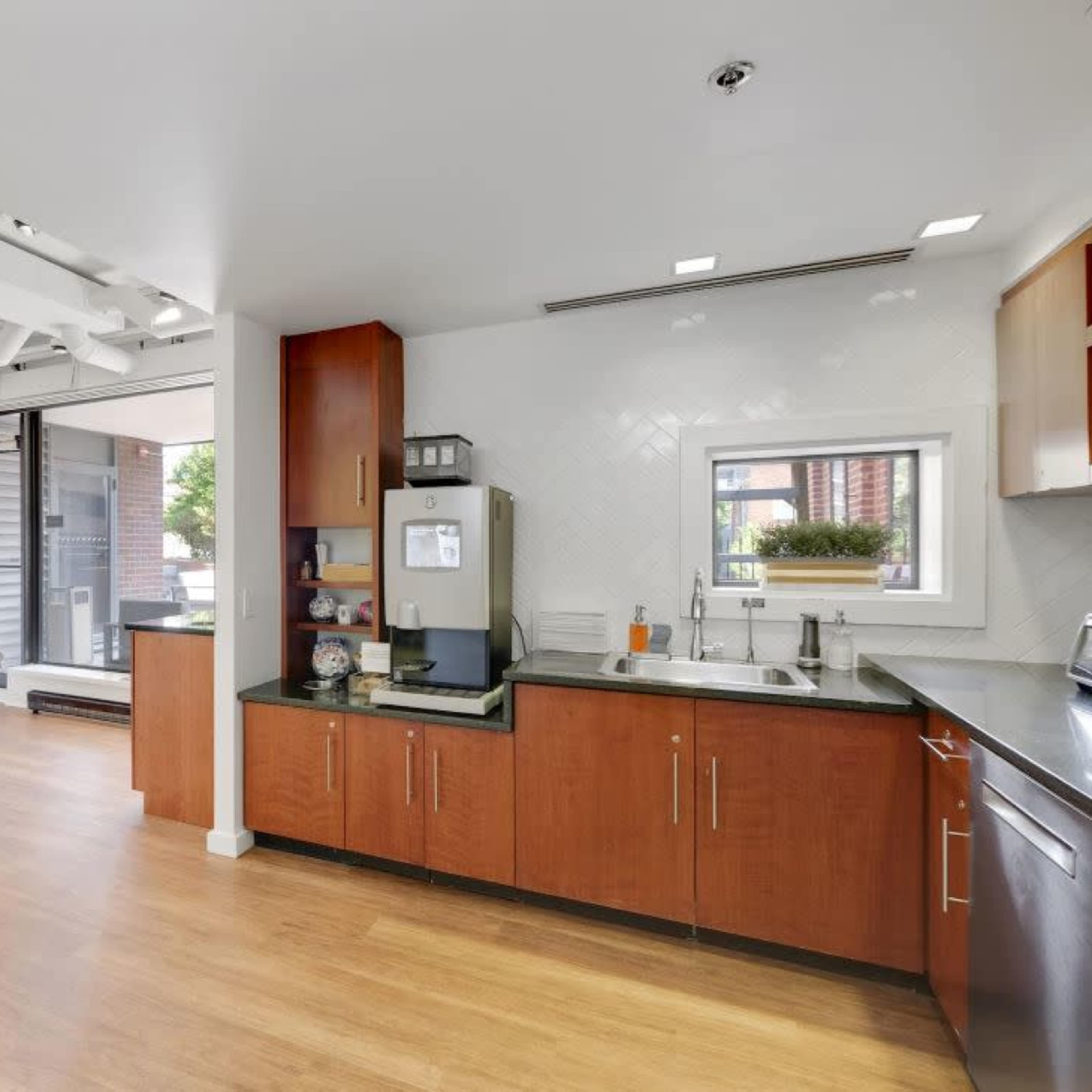 A modern kitchen with wooden cabinets, a round dining table, and a view of a cityscape through a nearby window.