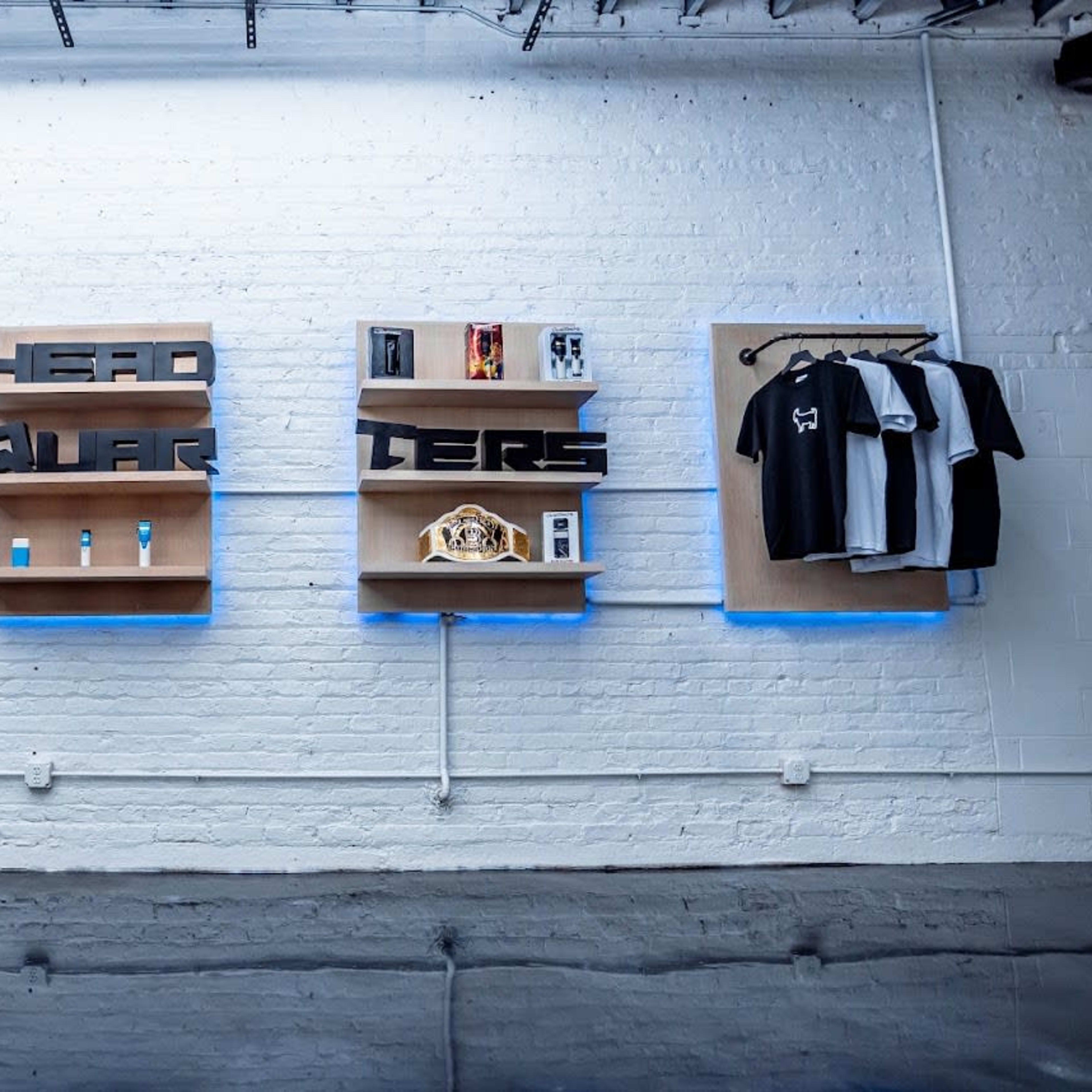 A retail space with neatly arranged clothing items on display alongside shelves featuring various products and a decorative championship belt.