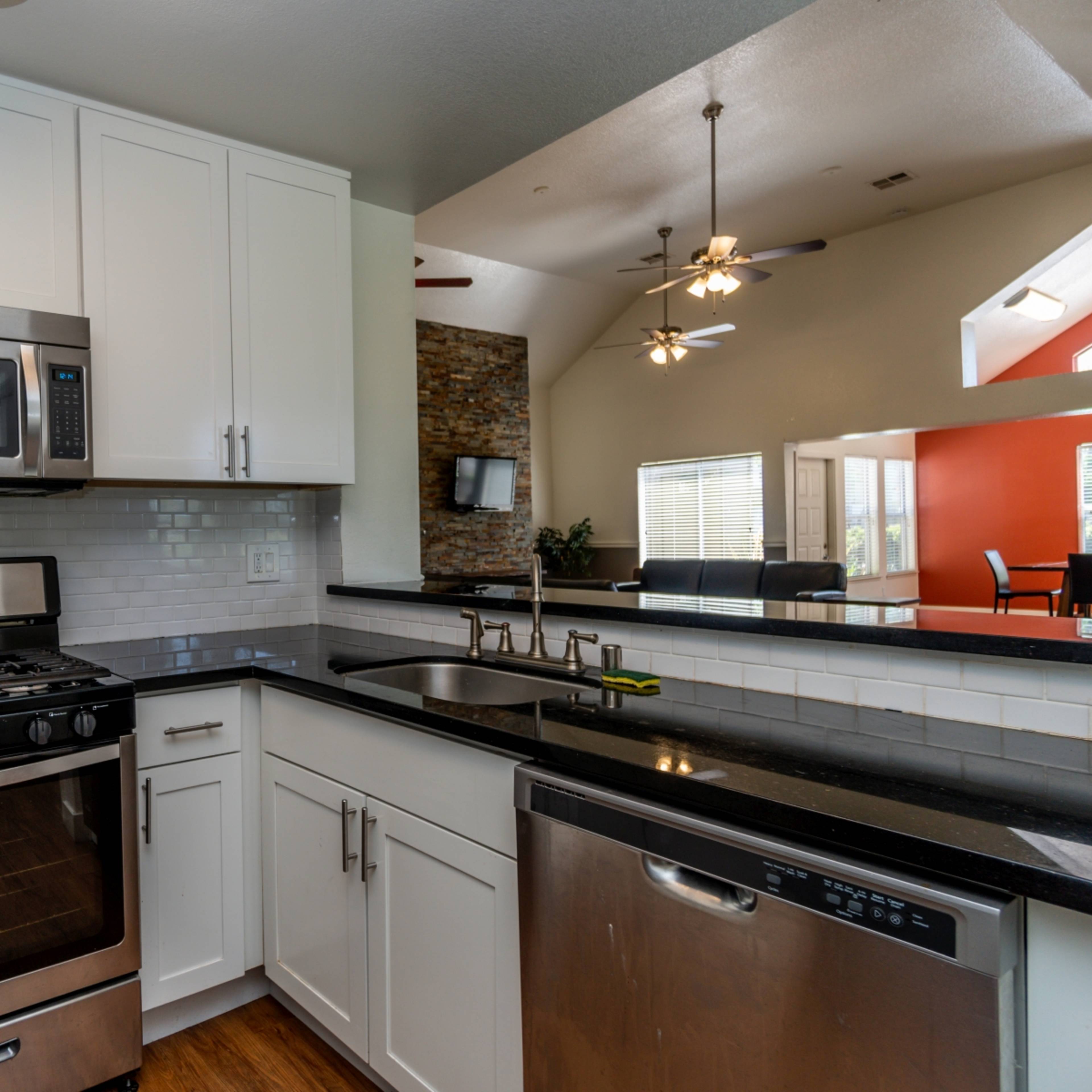A modern kitchen featuring stainless steel appliances, white cabinetry, and a black countertop.