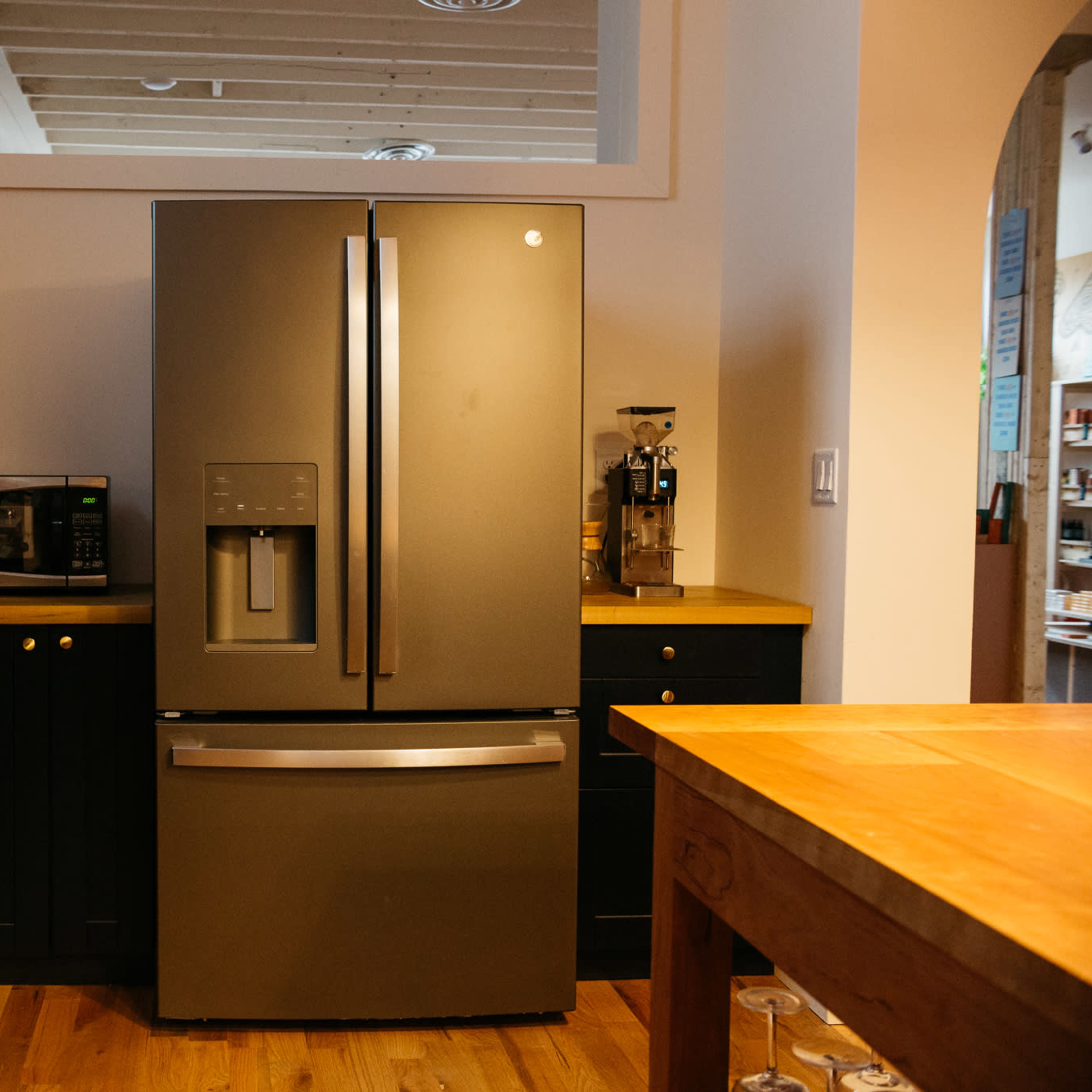 A modern kitchen featuring a dark refrigerator, a microwave, and wooden countertops.