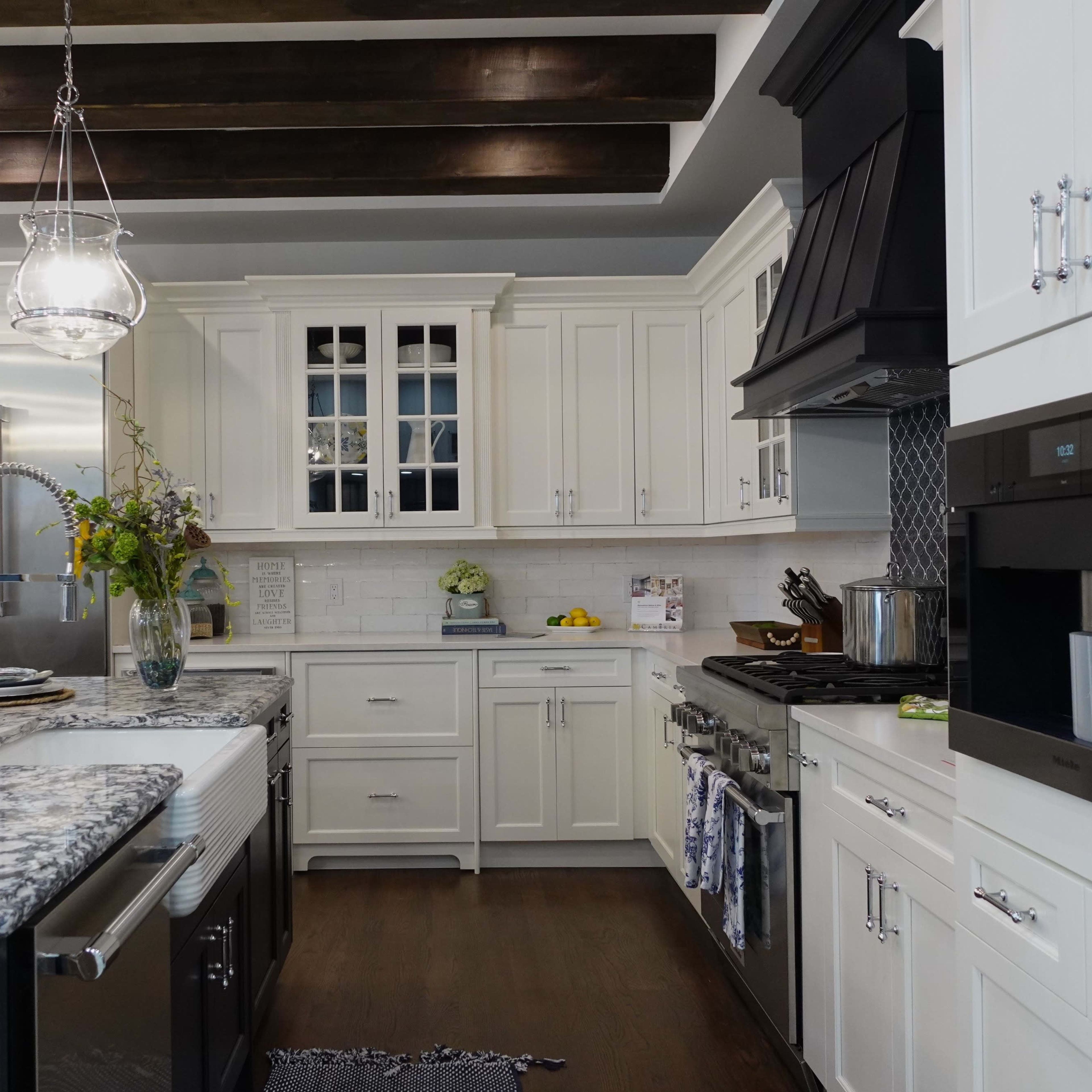 A modern kitchen featuring white cabinetry, a granite island, stainless steel appliances, and pendant lighting.