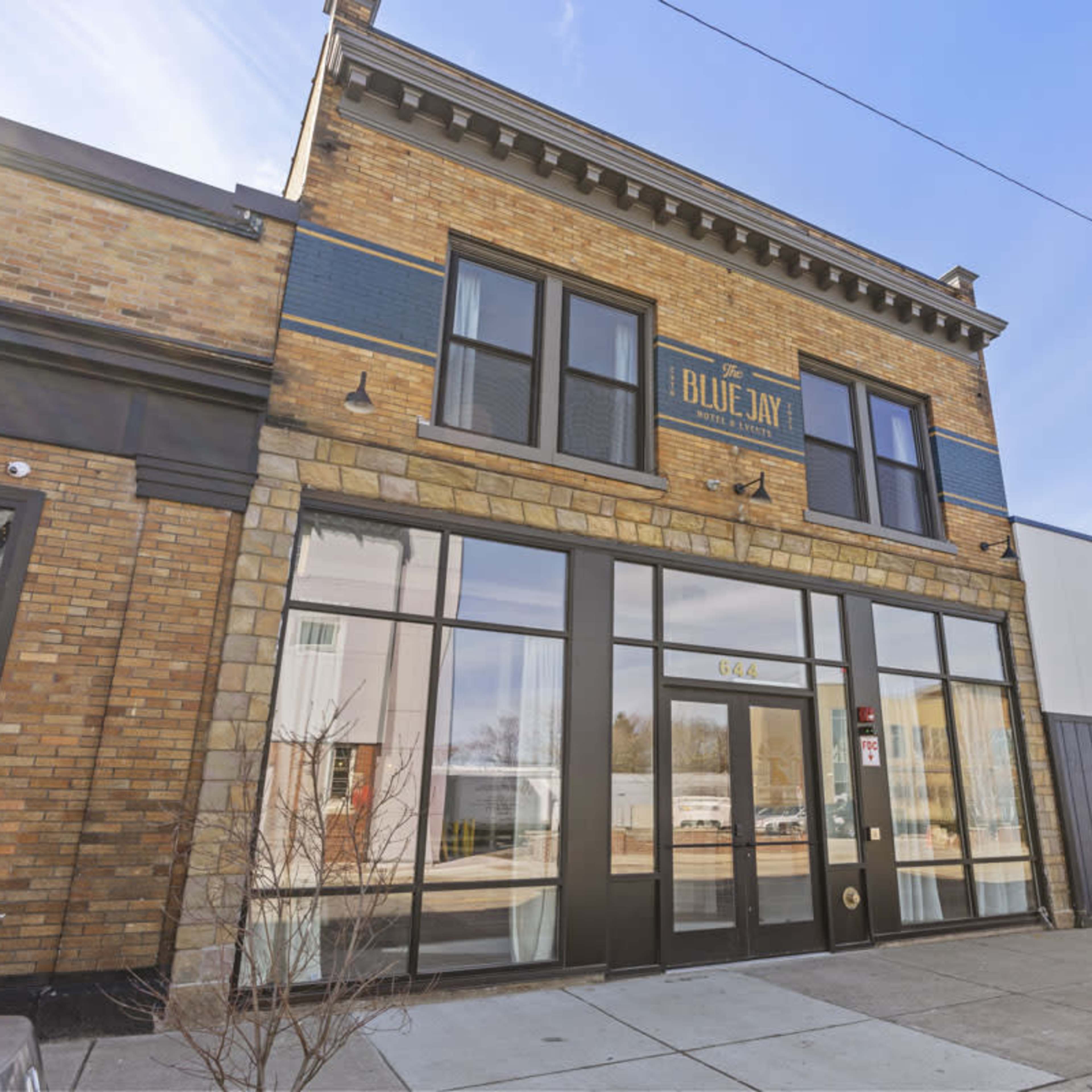 A two-story brick building with large glass windows, labeled "Blue Jay," located on a city street.