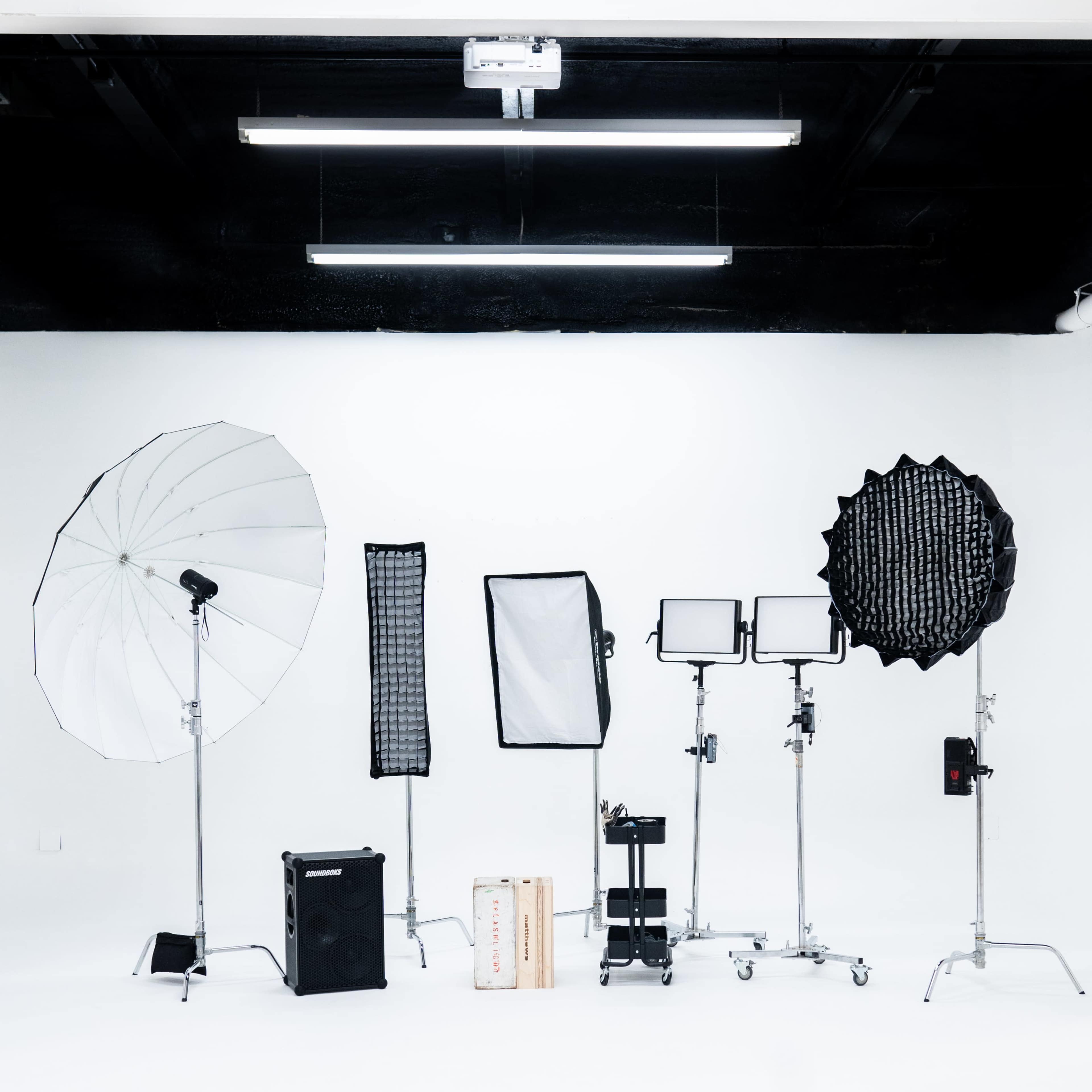 A photography studio setup with various lighting equipment arranged on a white backdrop.