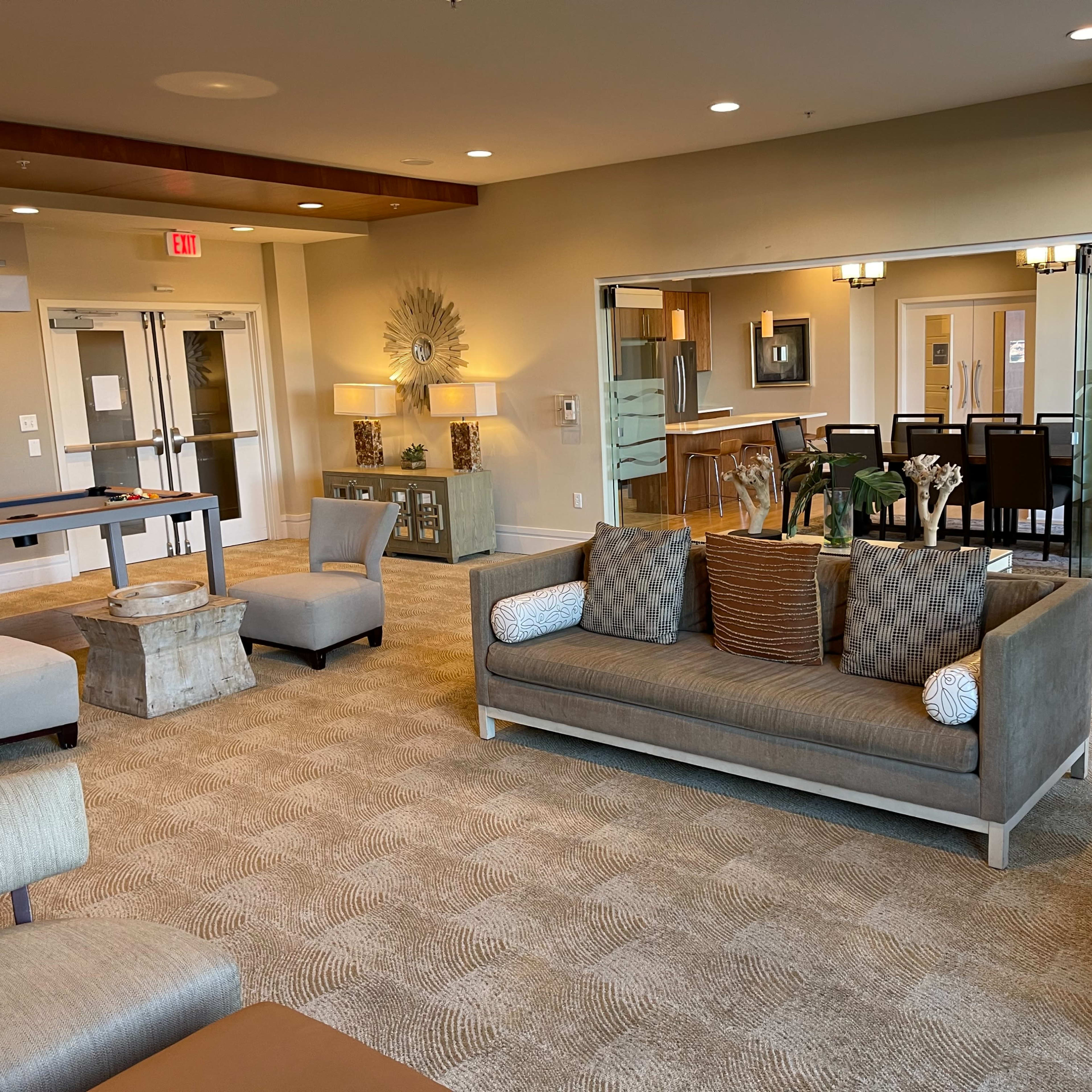 A modern common area with a seating arrangement that includes a sofa, armchairs, and a dining area in the background.