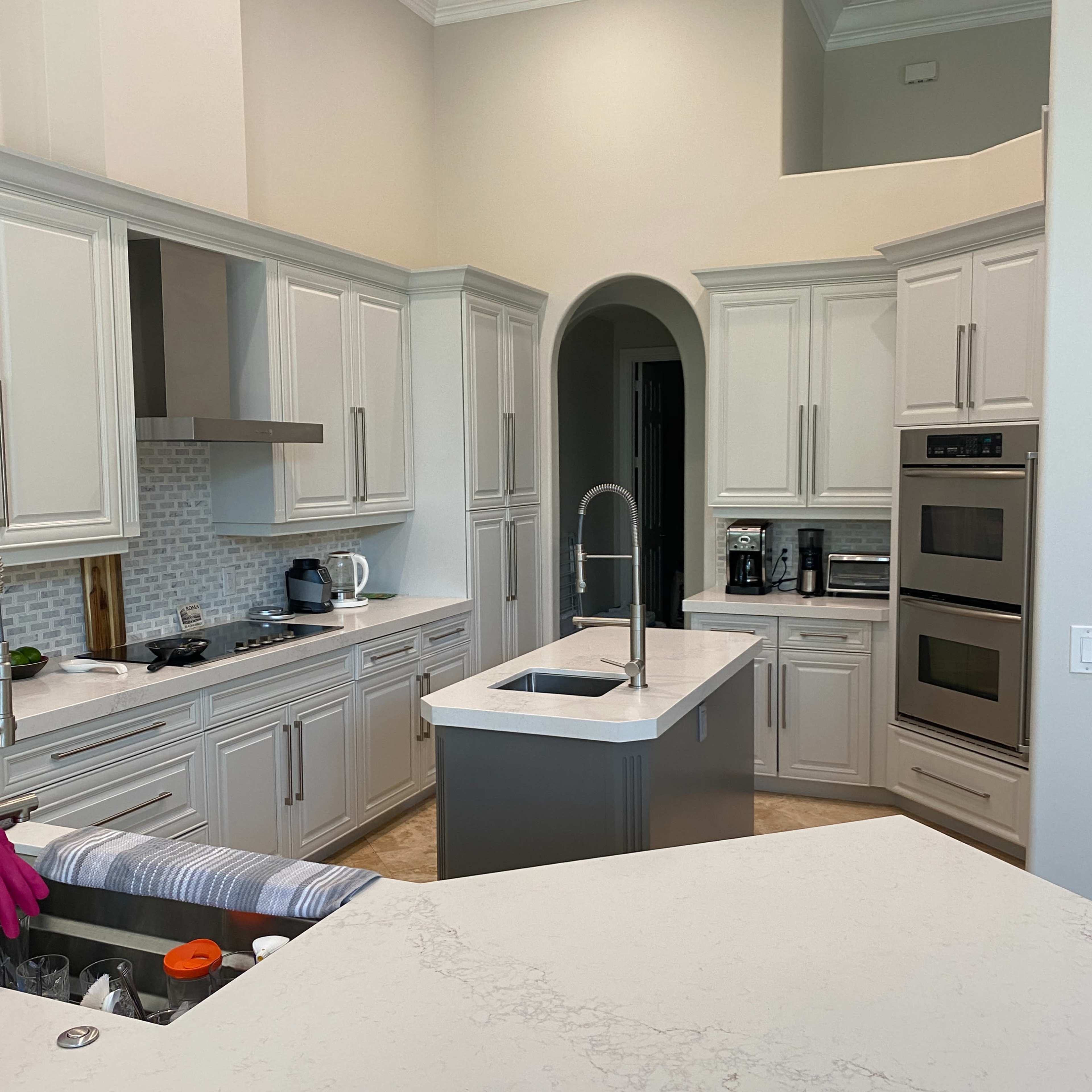 A modern kitchen featuring white cabinetry, a large island with a sink, and stainless steel appliances.