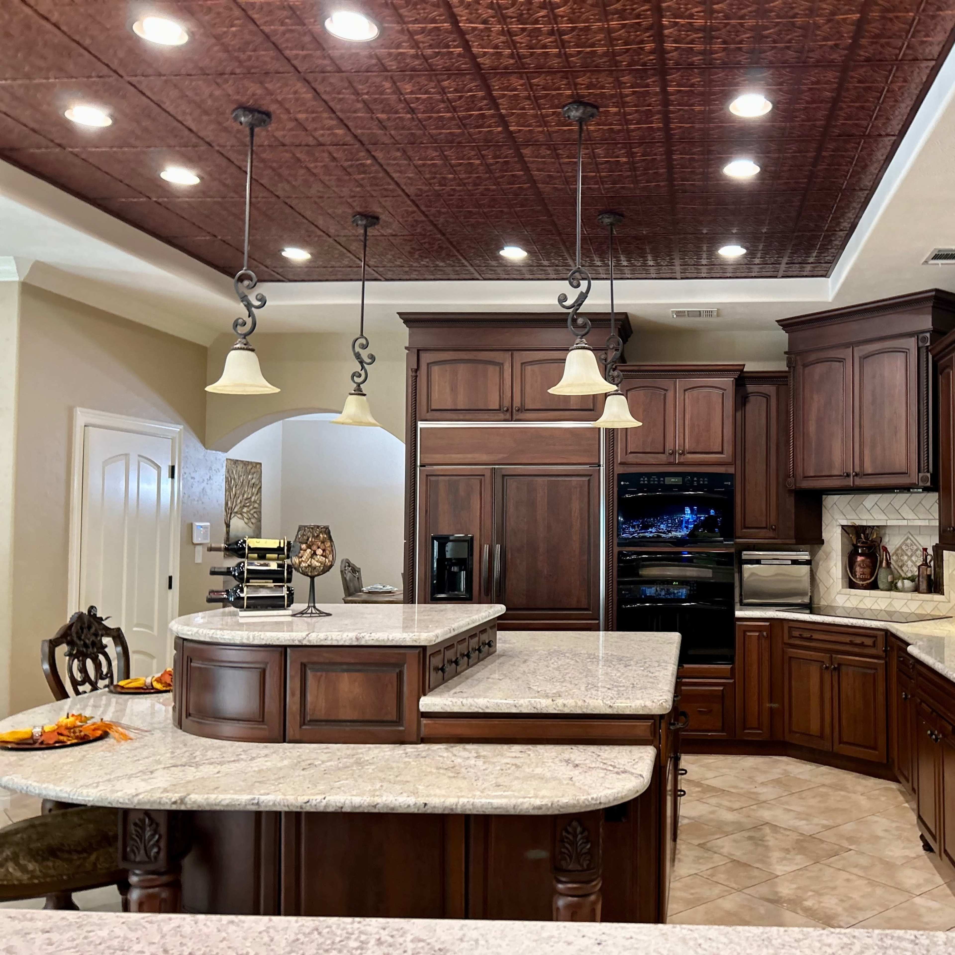 A spacious kitchen with dark wooden cabinetry, granite countertops, and pendant lighting above the central island.