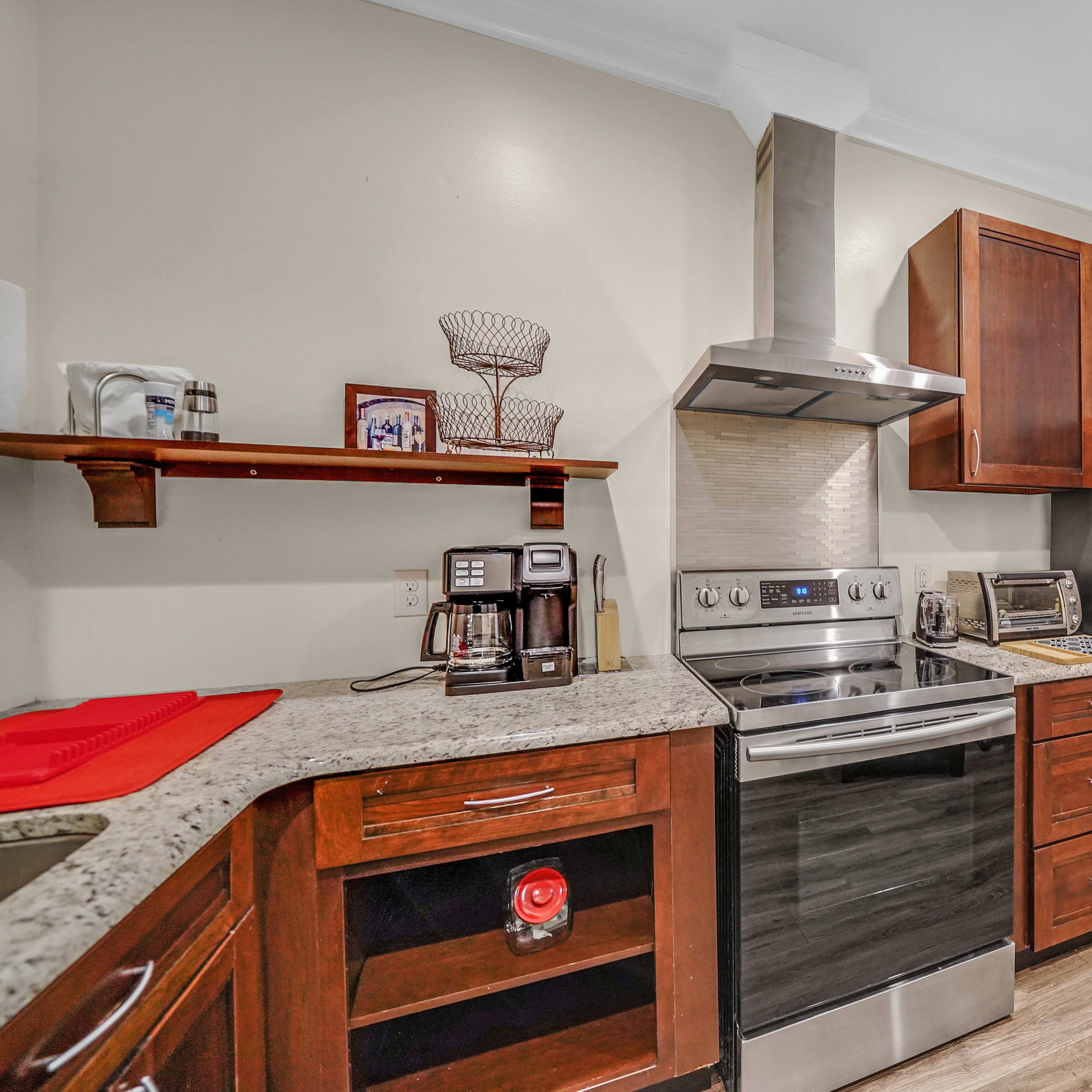A modern kitchen featuring stainless steel appliances, wooden cabinetry, and a granite countertop.