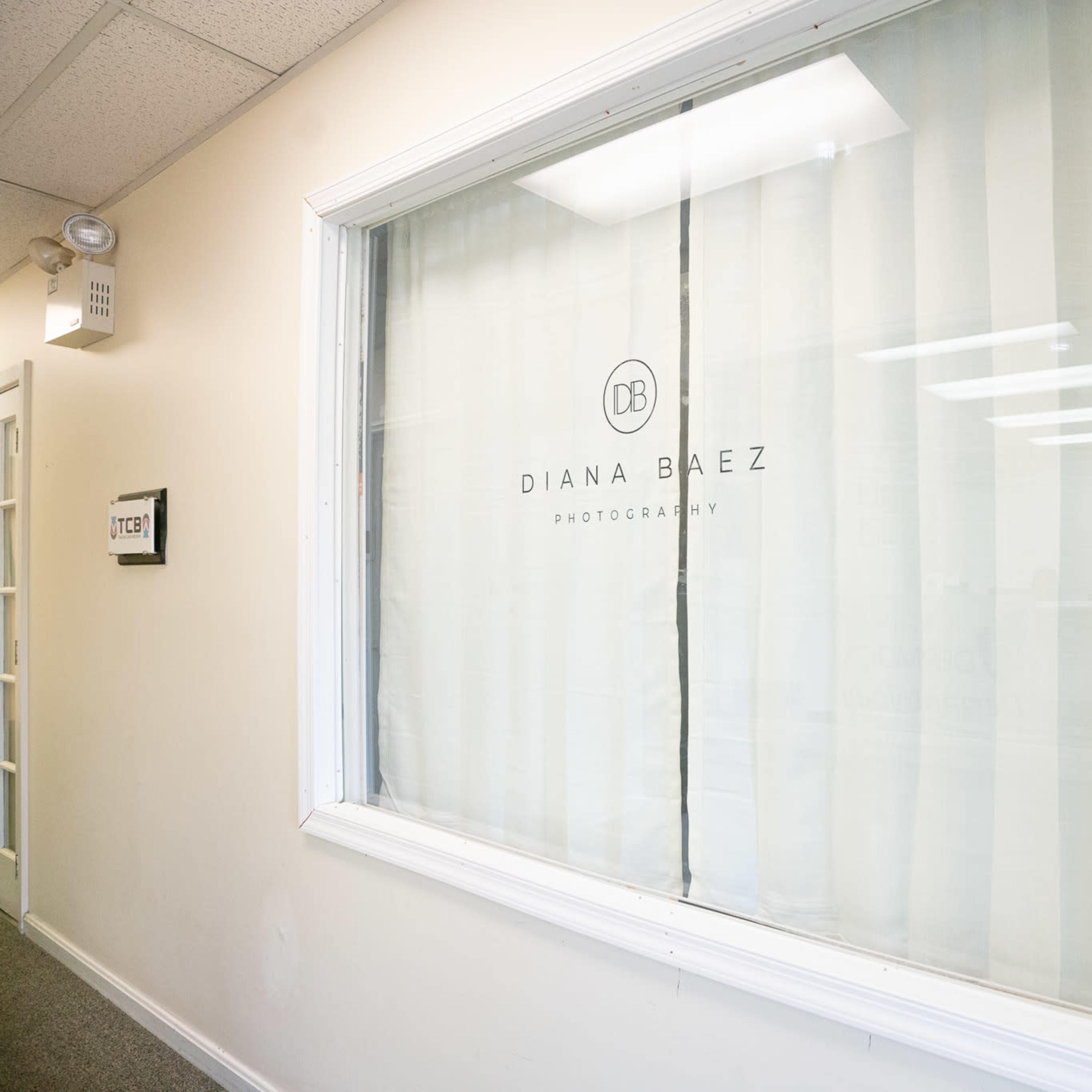 A window with a sign reading "Diana Baez Photography" on a white curtain.