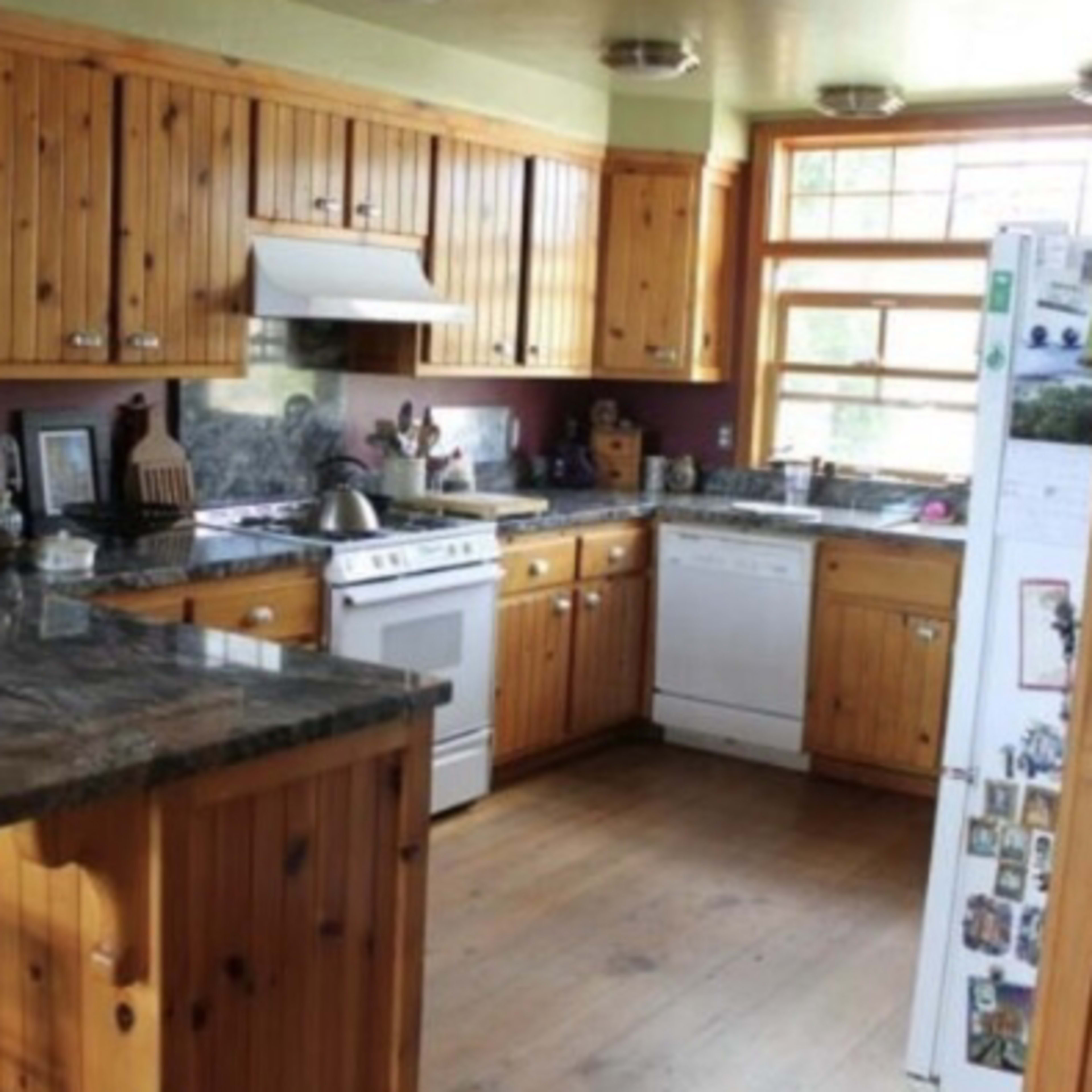 A kitchen featuring wood-paneled walls and cabinets, a central island with a granite countertop, and modern appliances.