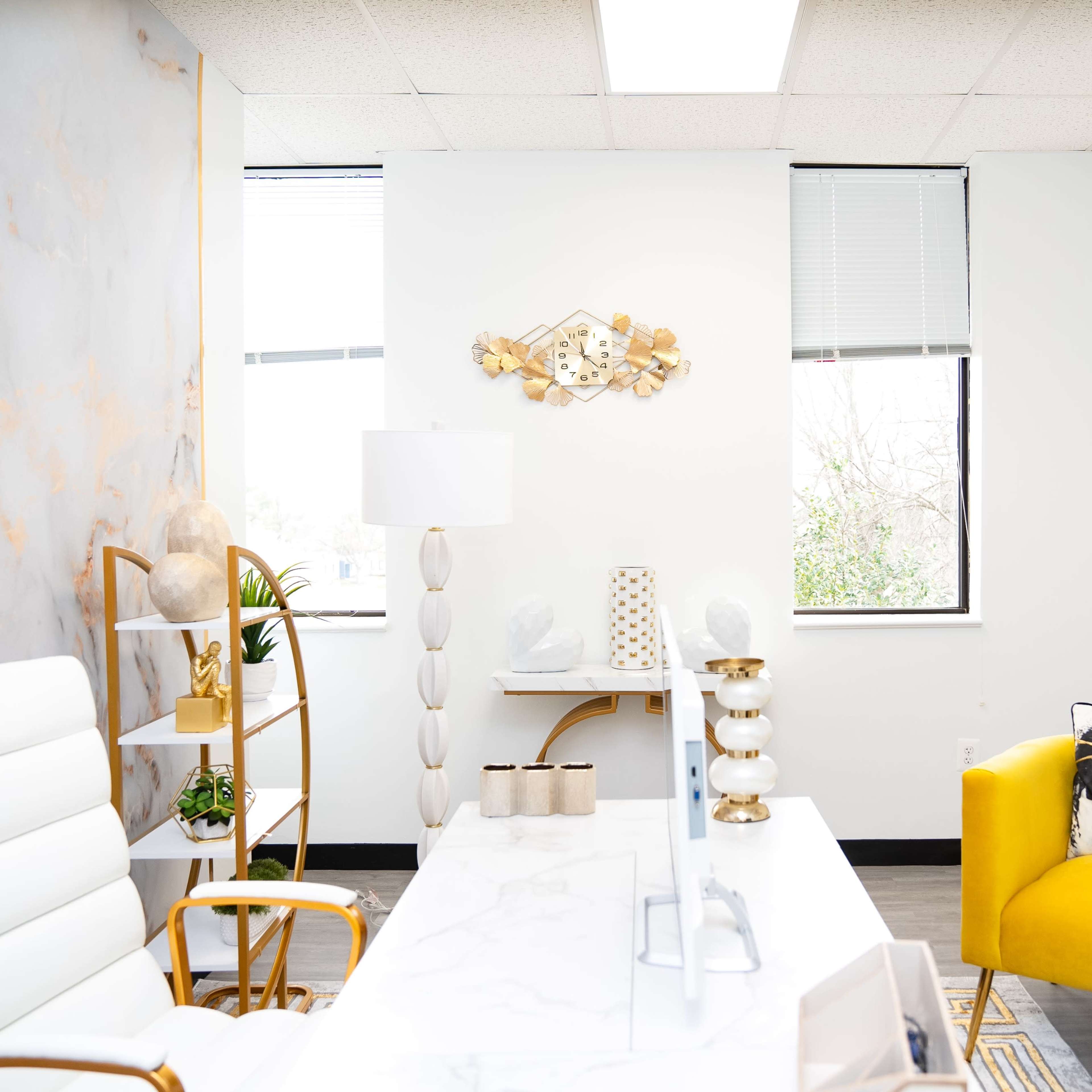 A modern office space featuring a white marble desk, a yellow accent chair, and decorative wall art.