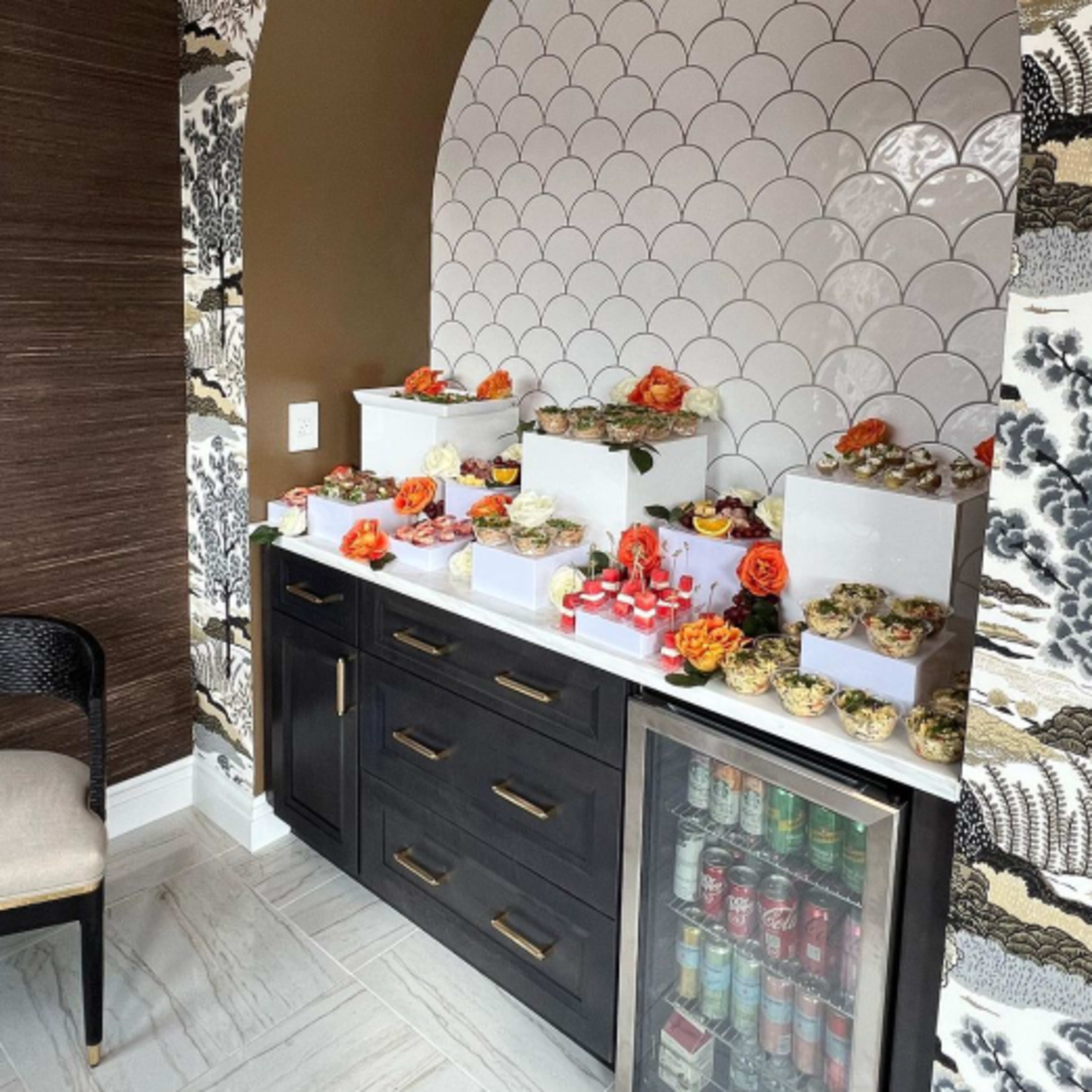 A decorative niche with several tiered displays of food arranged on a dark cabinet against a patterned wall.