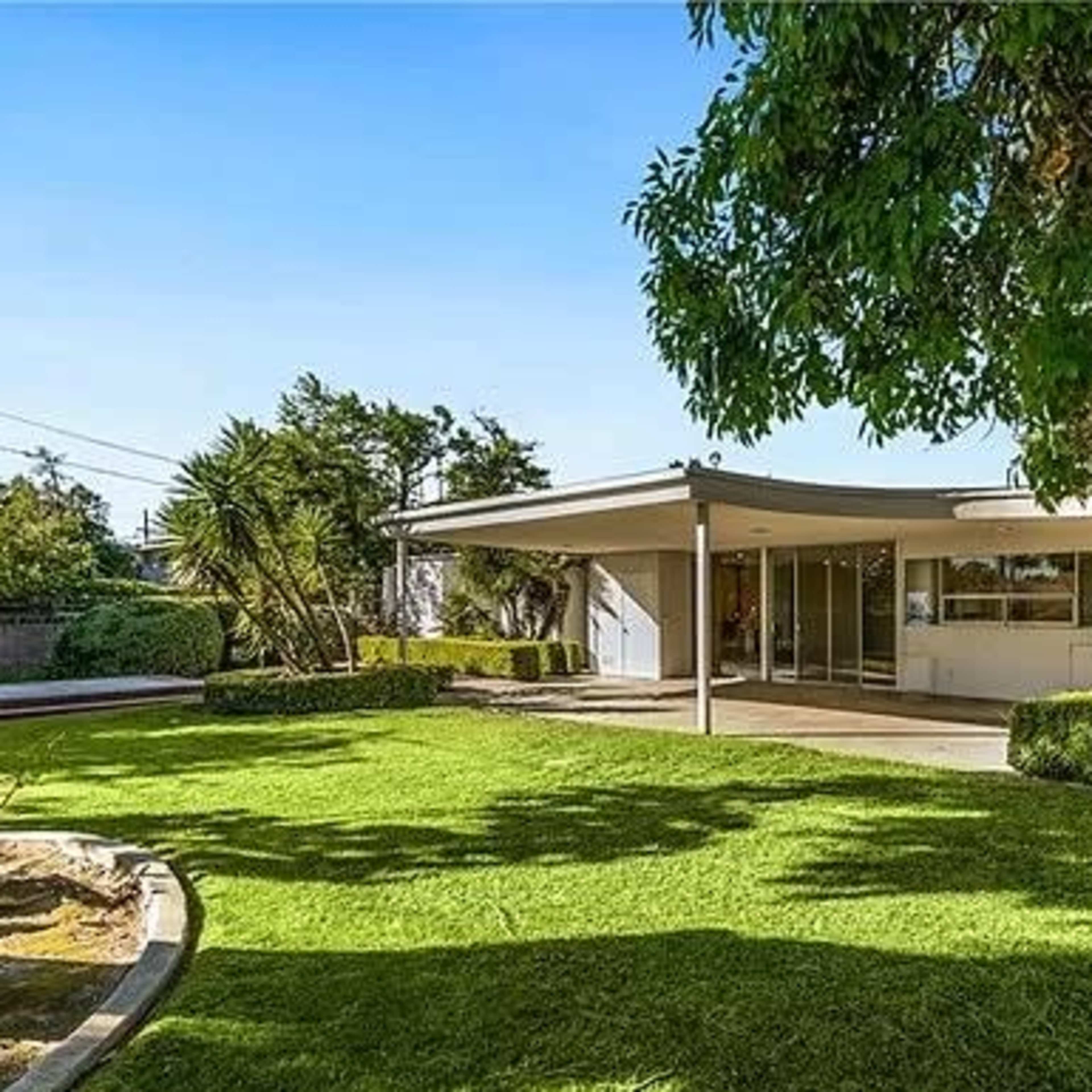 A modern single-story home is set amidst a well-maintained lawn and greenery.
