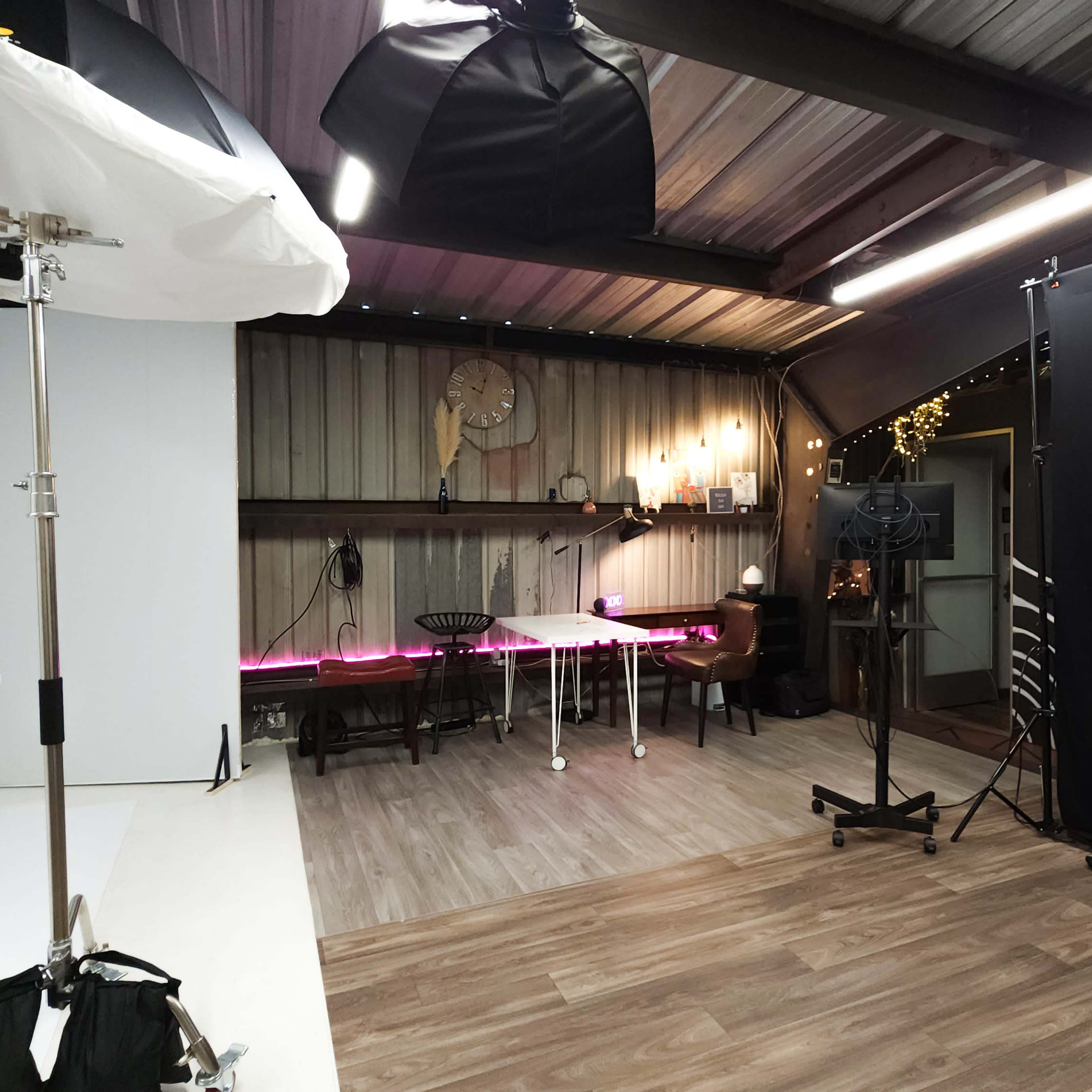 A photography studio with various lighting equipment, a backdrop, and tables arranged for photo shoots.
