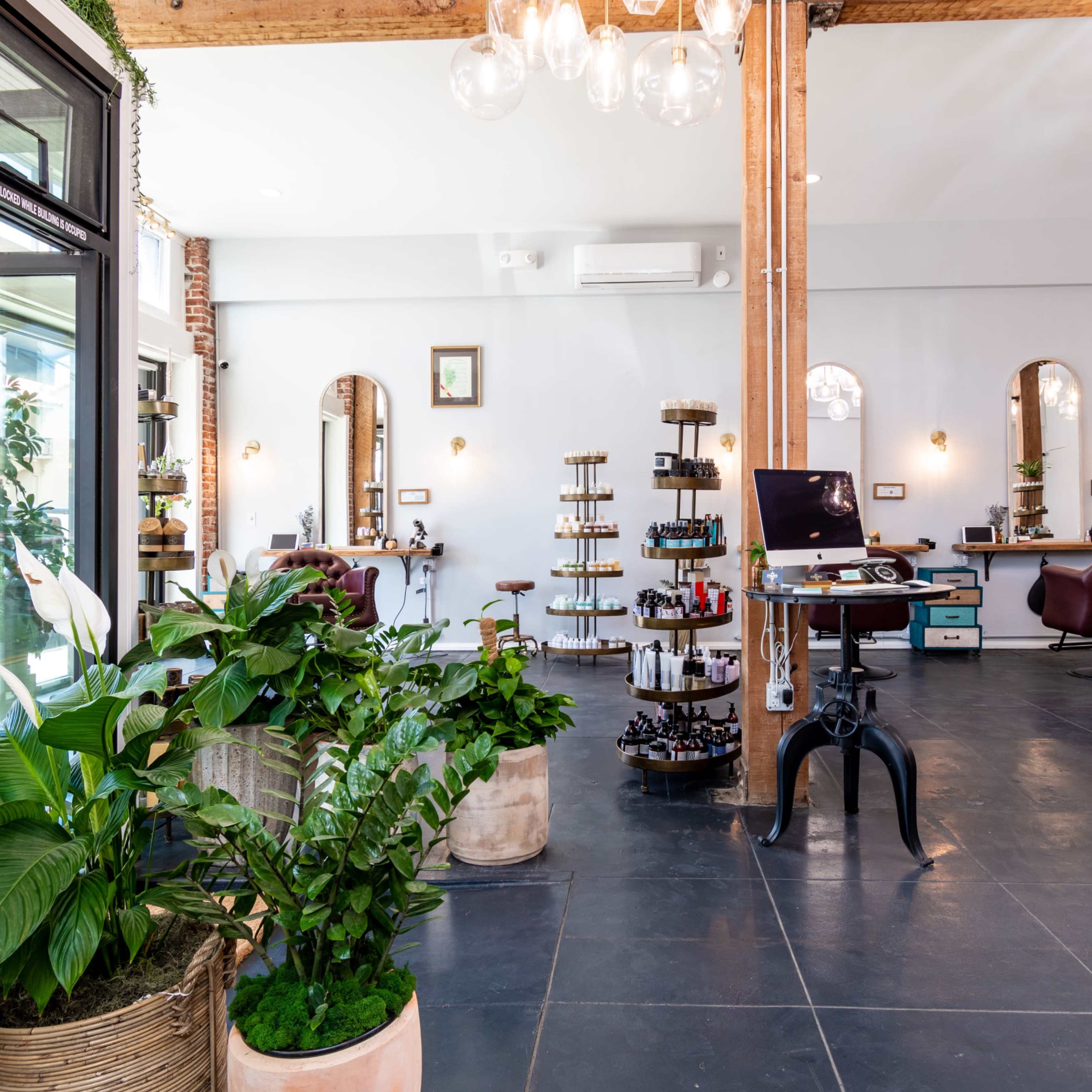 Large open gallery like salon space with brick and wood beams, high ceilings and many plants. Image in Central LA, Los Angeles, CA