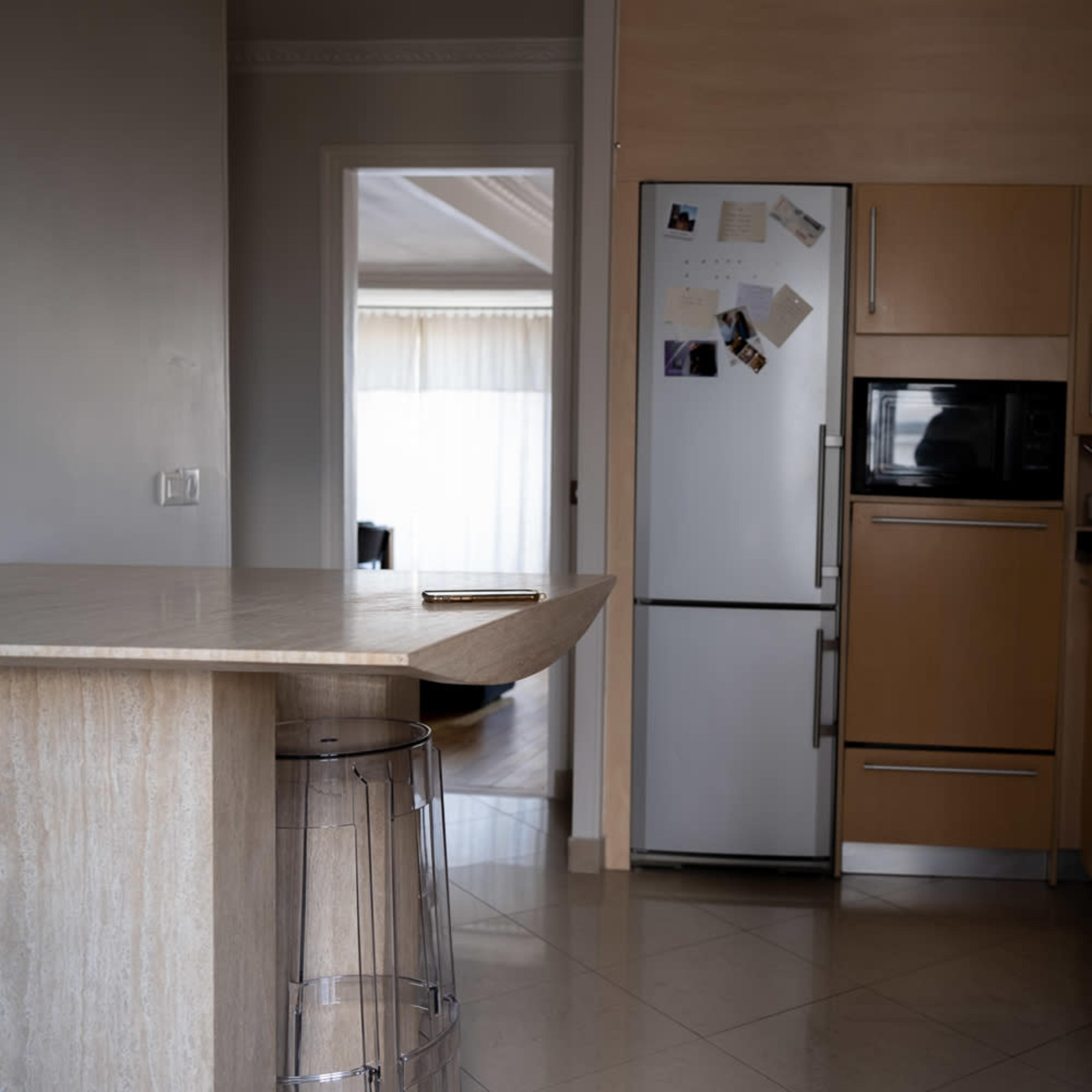 A modern kitchen with wood cabinetry, a stainless steel refrigerator, and a bar-height countertop.