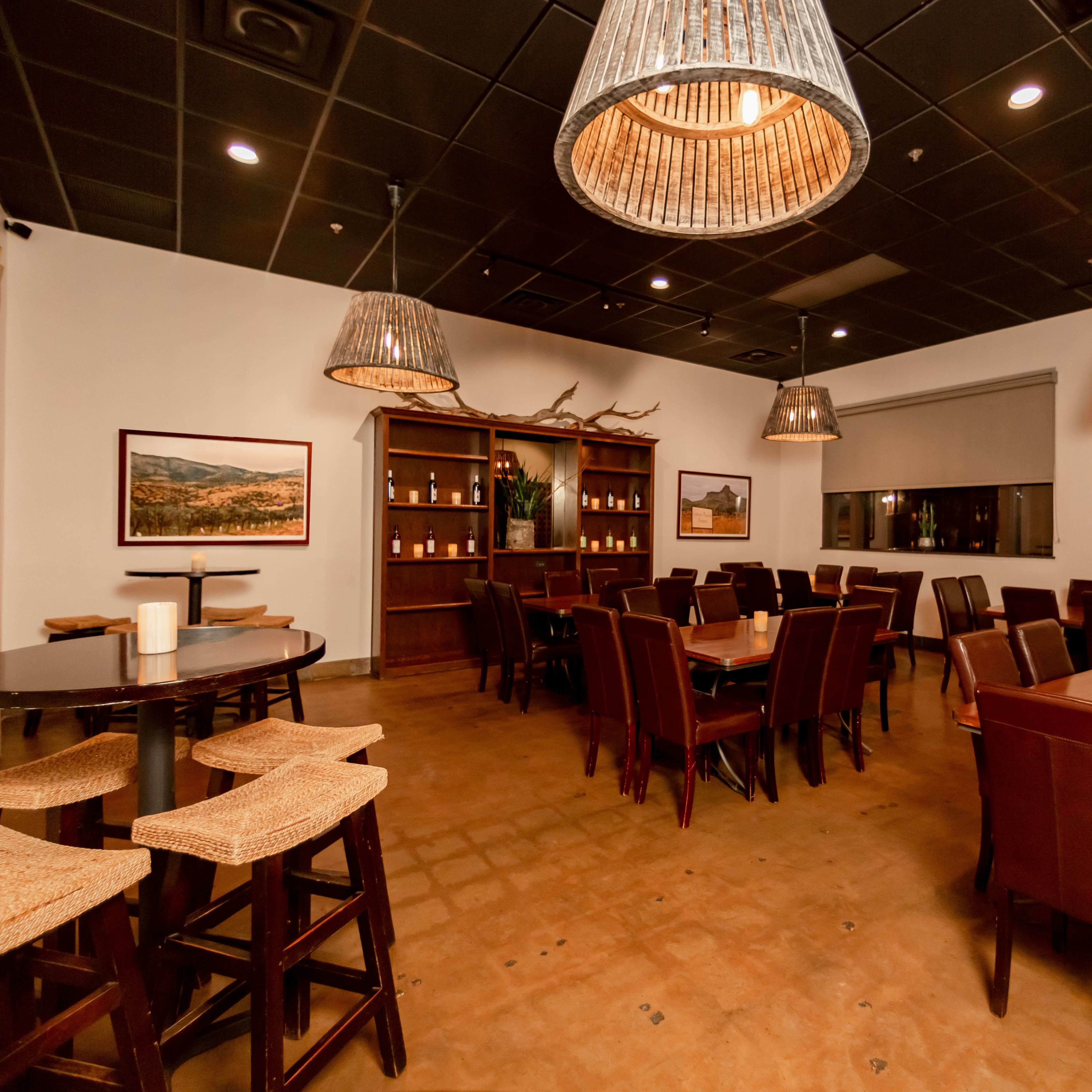 A spacious restaurant interior with wooden tables, brown chairs, and decorative pendant lights hanging from the ceiling.