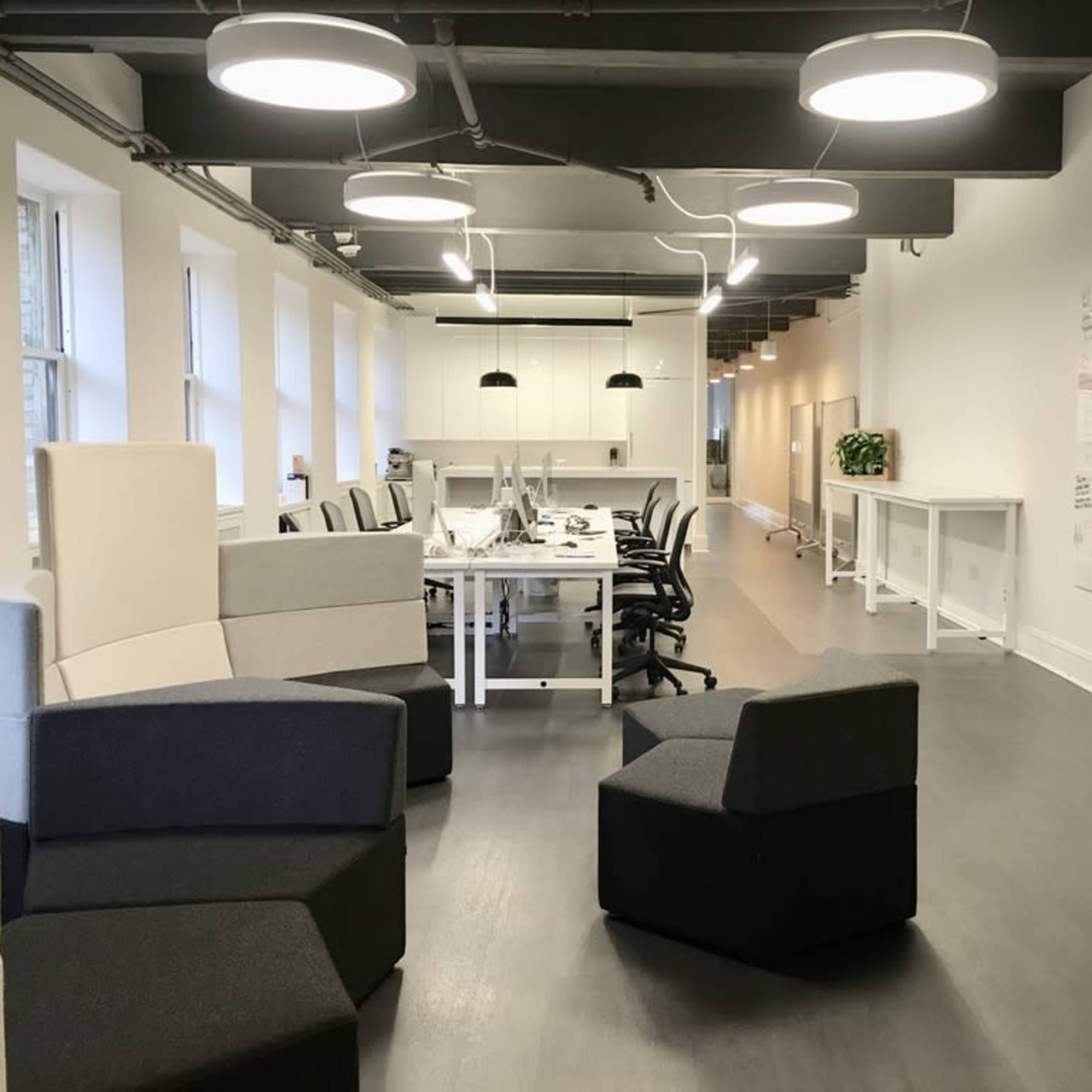 A modern office space with a row of desks and a whiteboard covered in notes, surrounded by distinctive seating arrangements.