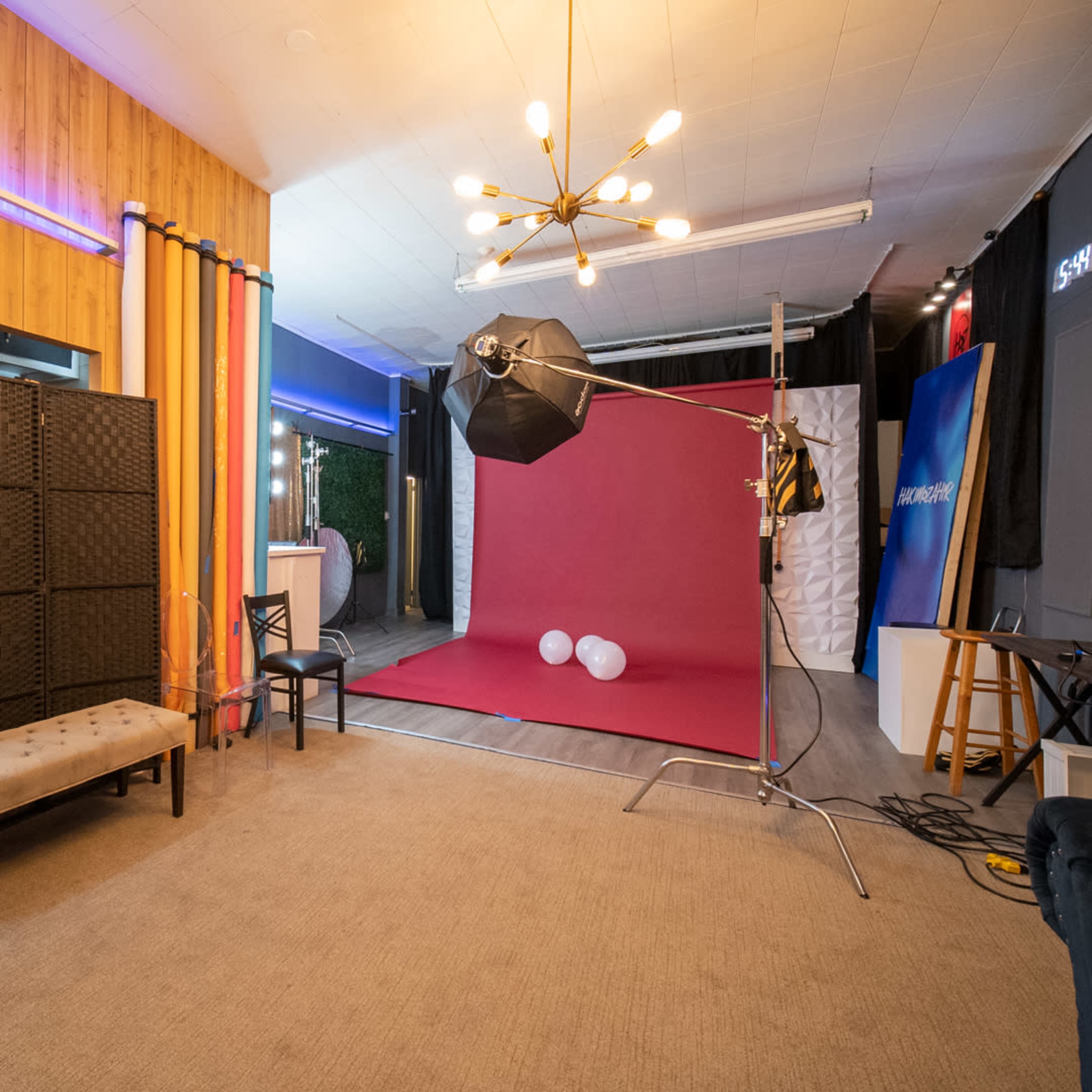 A photography studio with a backdrop, lighting equipment, and decorative elements like curtains and furniture.