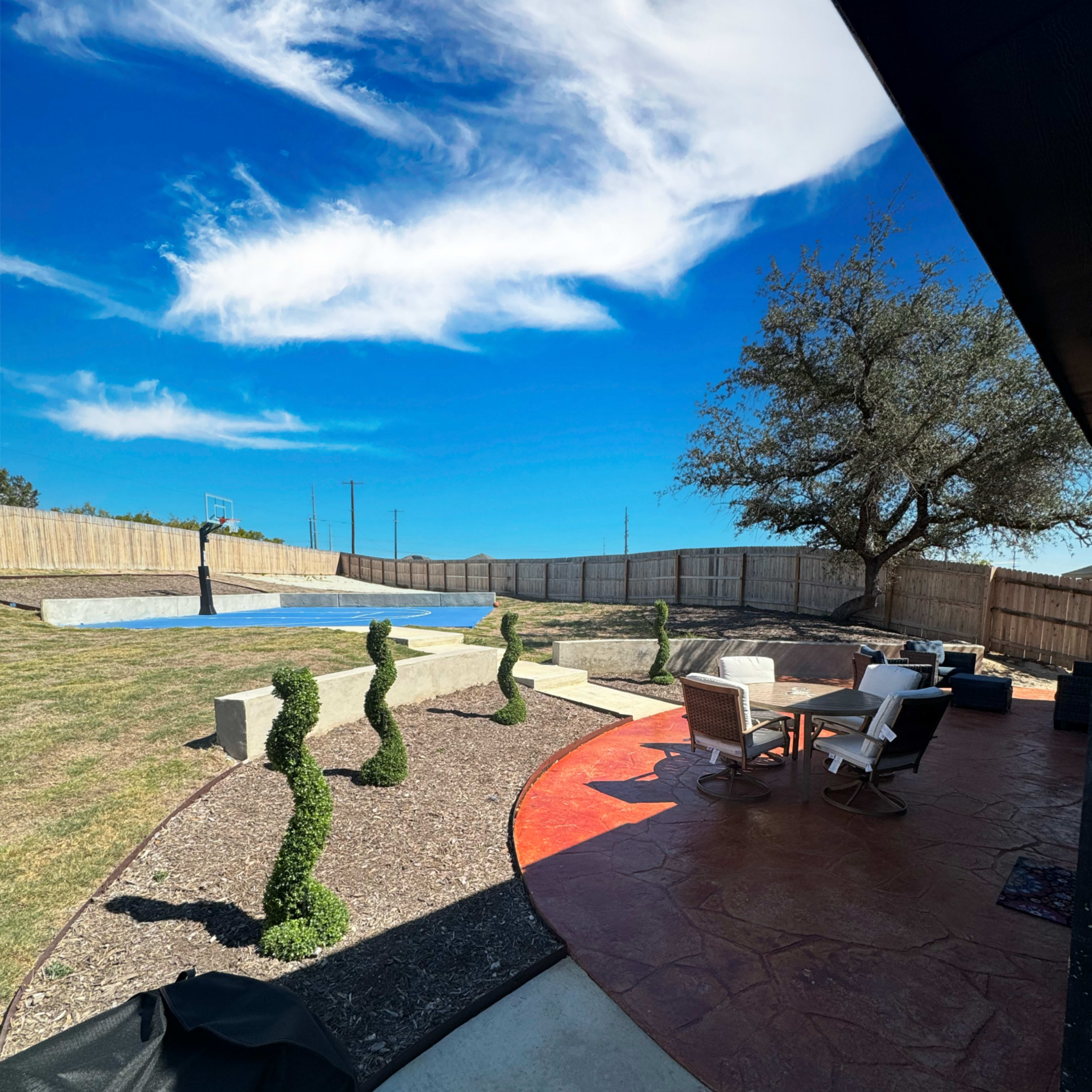 A backyard with distinct topiary sculptures, a swimming pool, and outdoor seating under a clear blue sky.