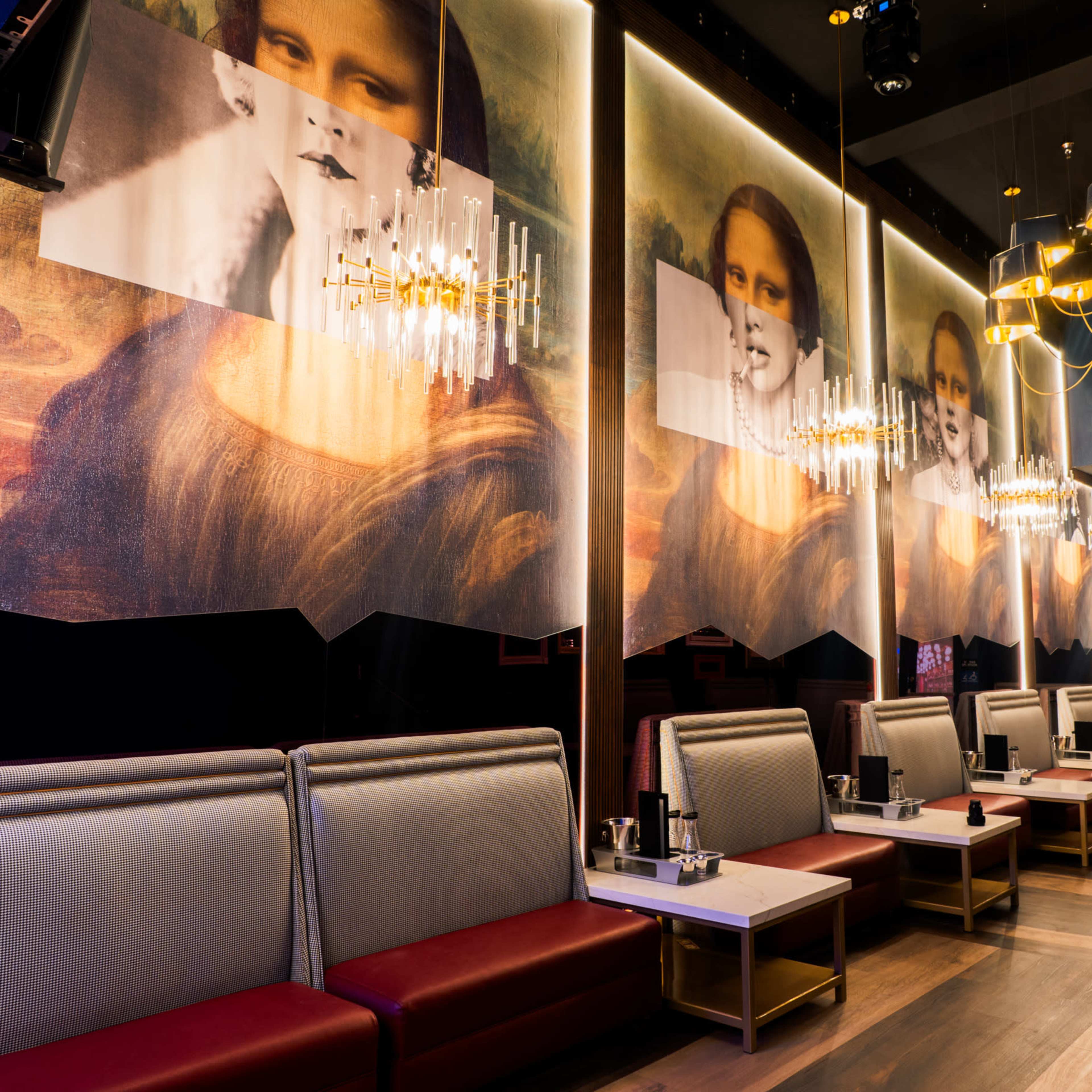 A modern interior of a restaurant featuring large murals of the Mona Lisa on the walls, with elegant seating and hanging light fixtures.