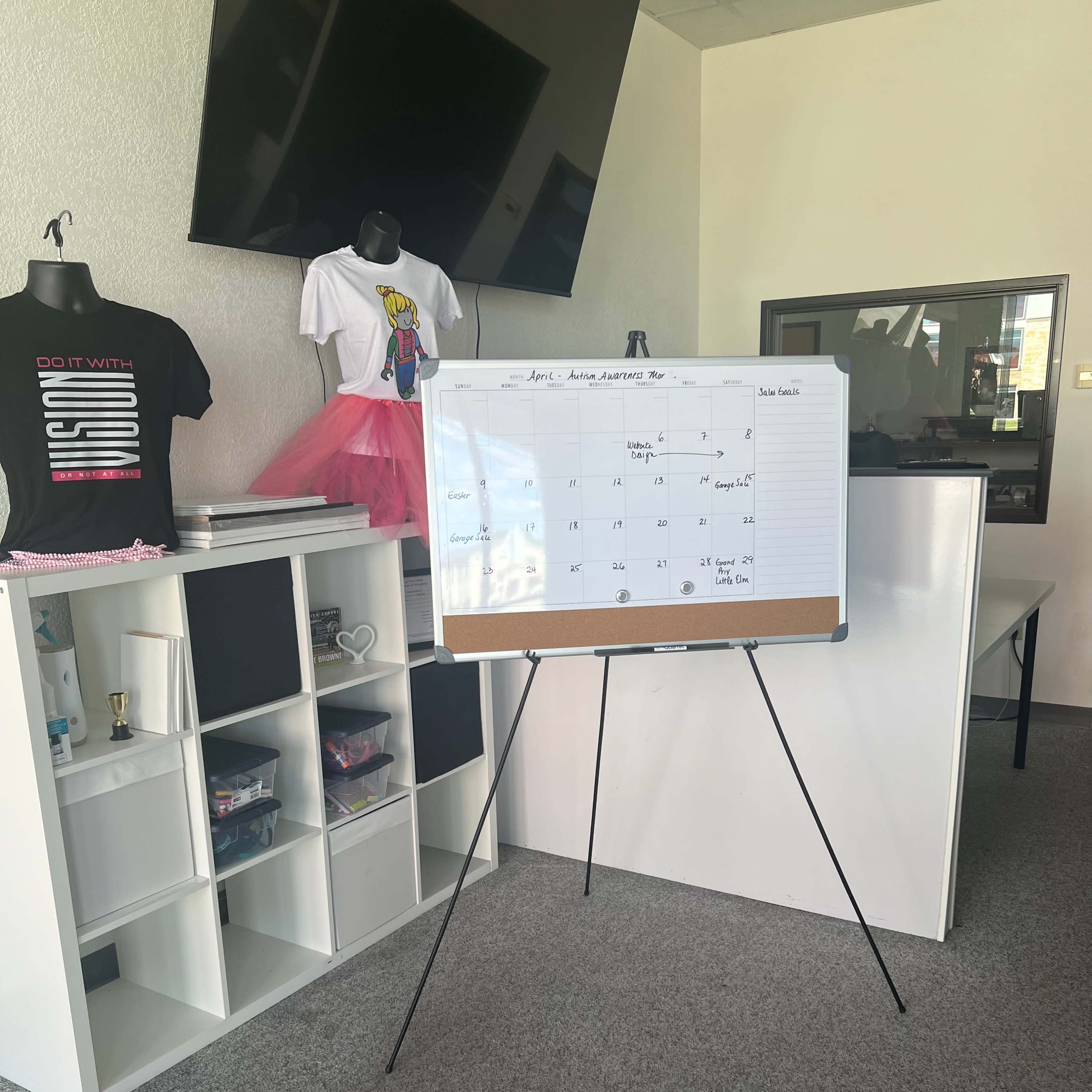 An organizational space featuring a calendar on an easel, clothing displays, and storage cubes.