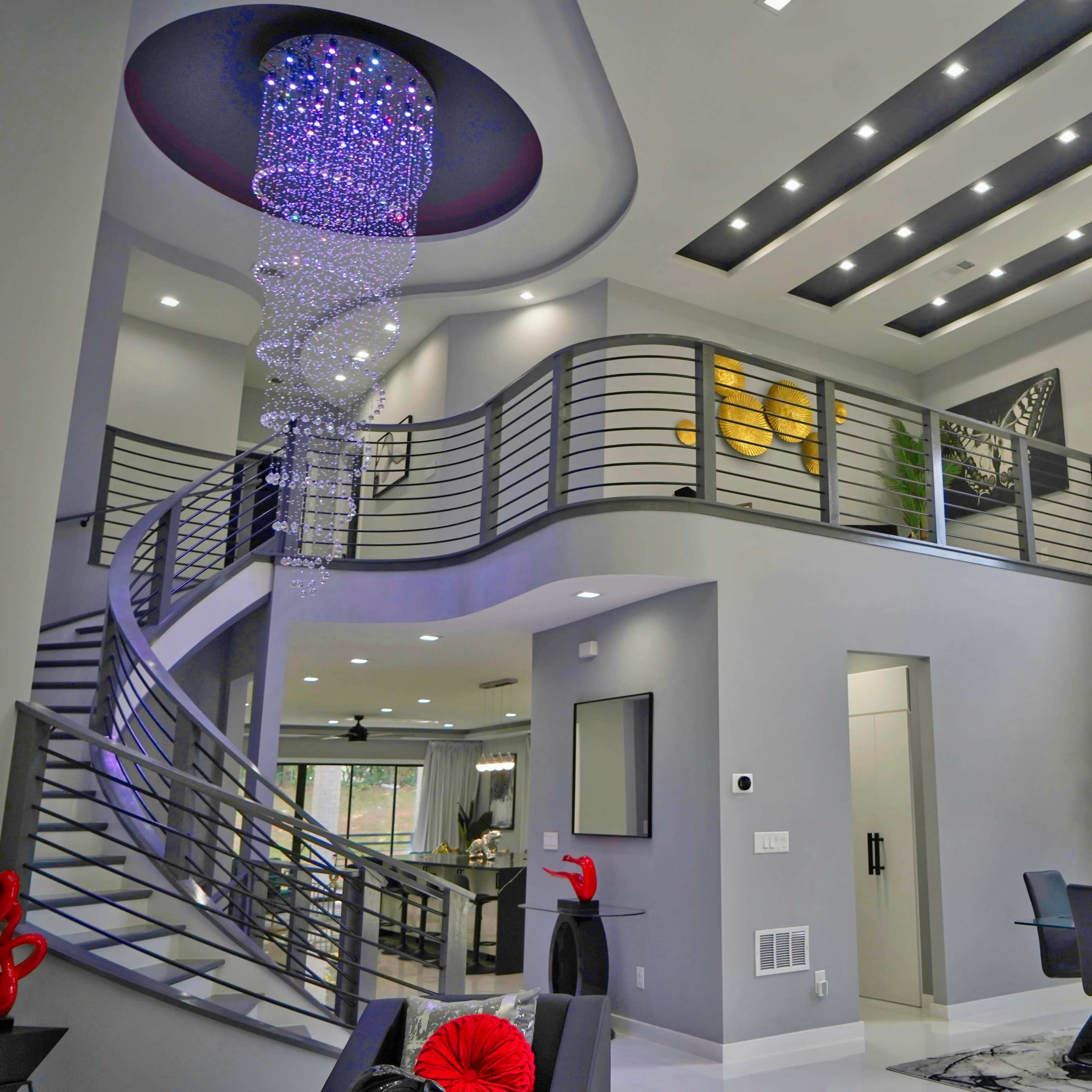 A modern interior featuring a spiral staircase, a large chandelier, and a dining area with sleek furniture.