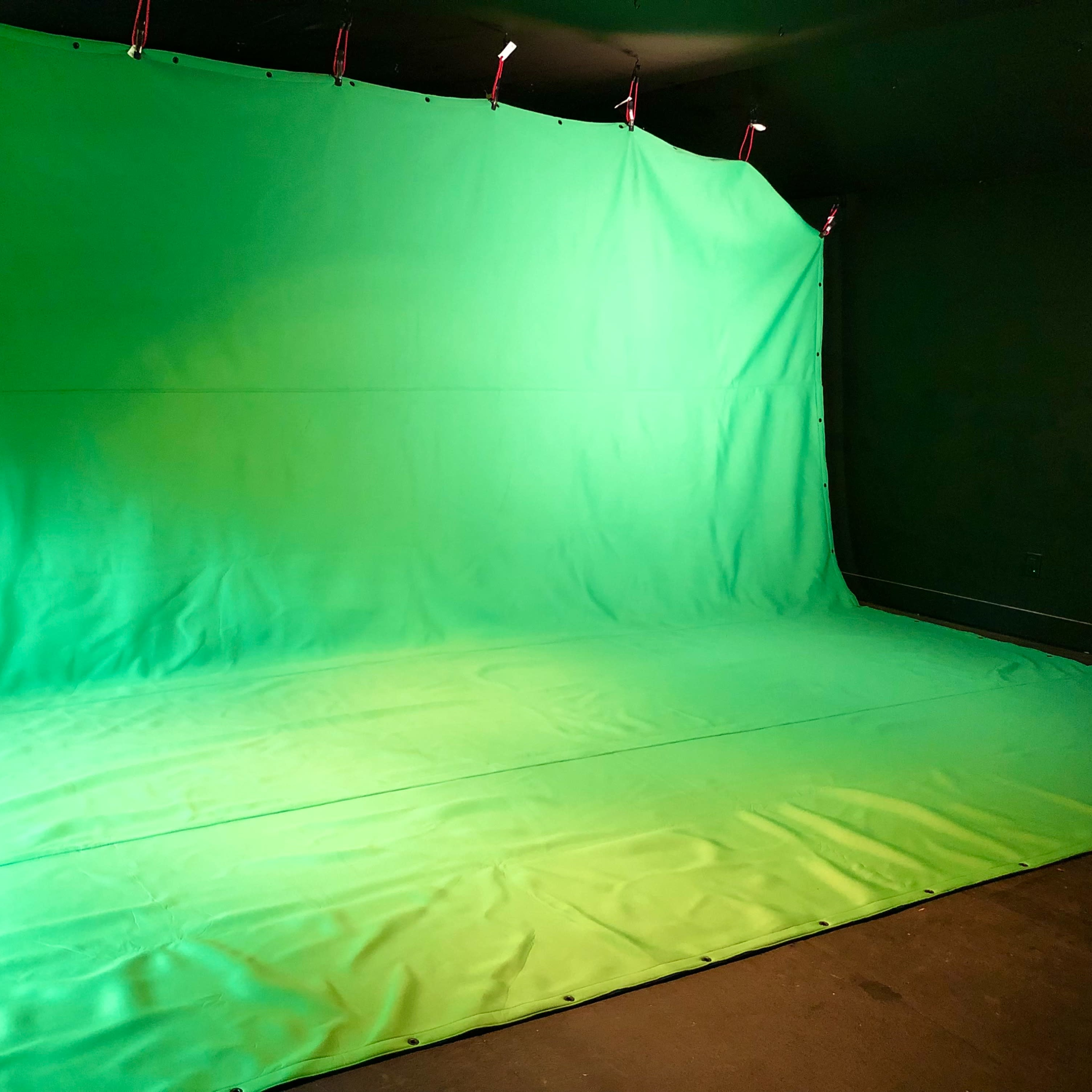 A large green backdrop draped across a wall and floor, commonly used for chroma key photography or video production.