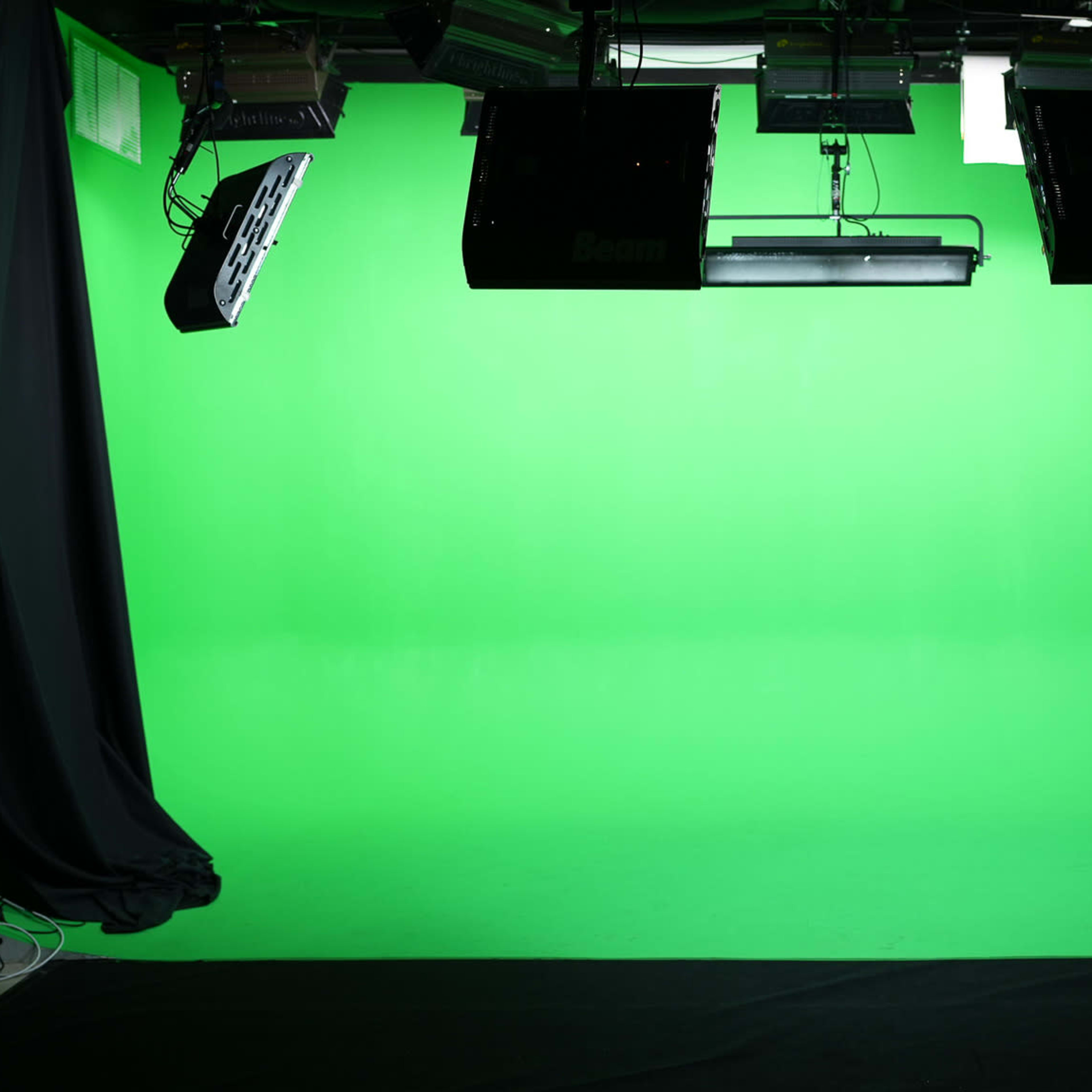 A studio setup with a bright green backdrop and overhead lighting fixtures.