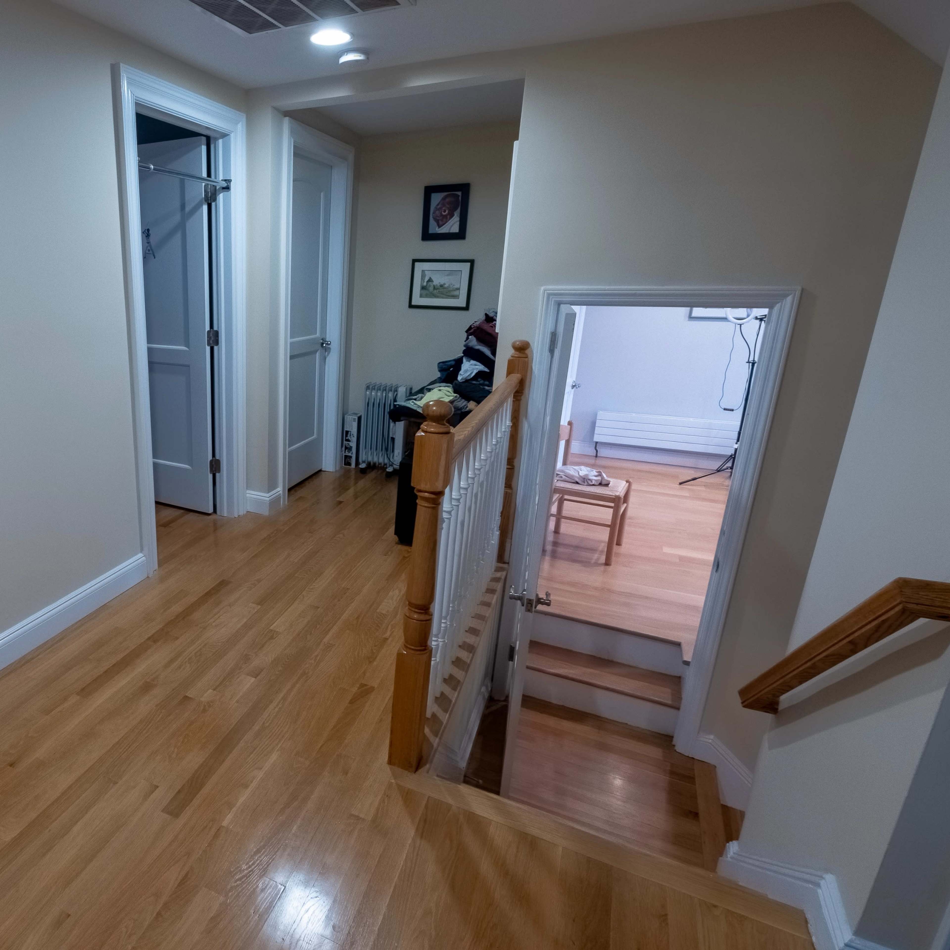 A wooden hallway with a map of the United States on the wall, leading to a staircase and several doorways.