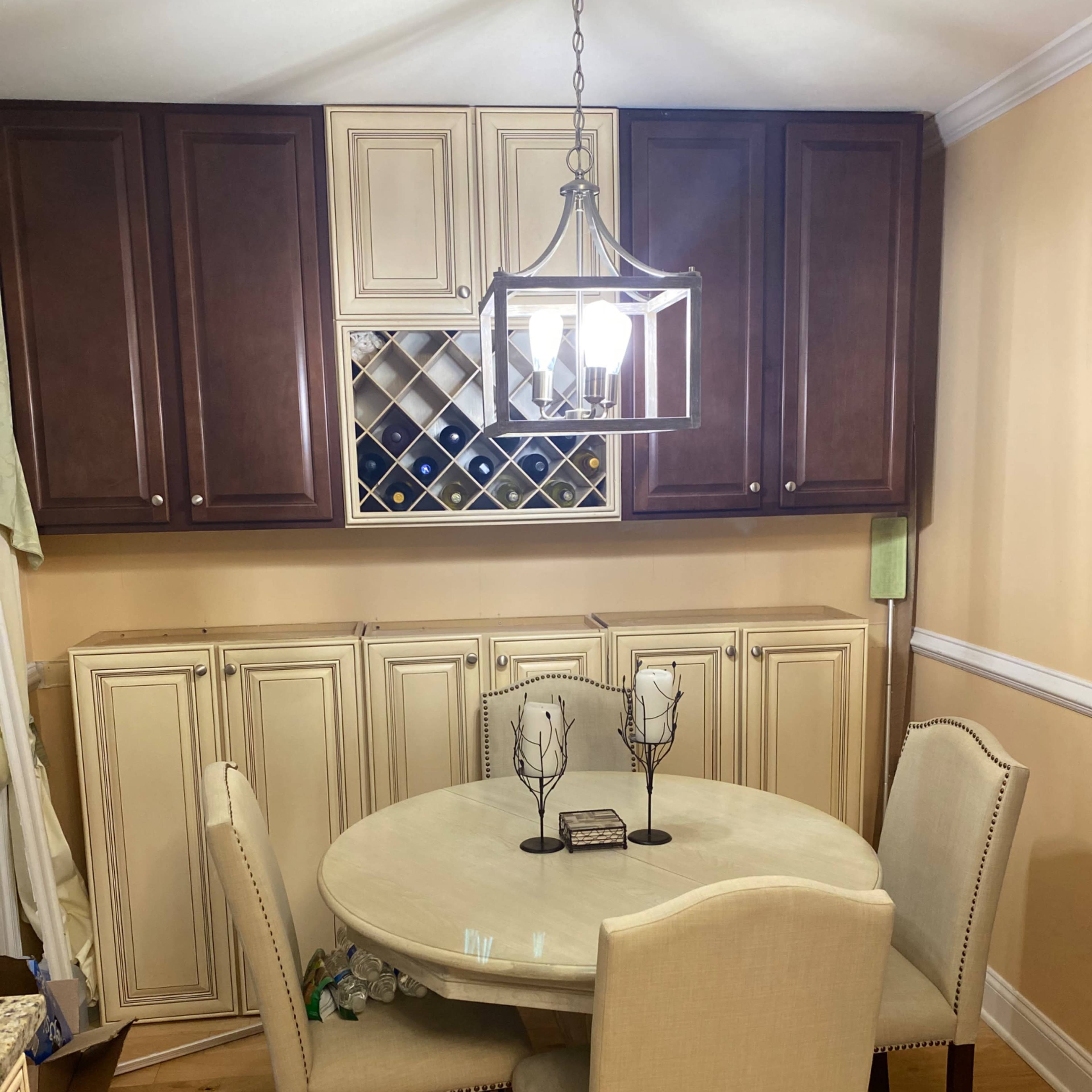 A small dining area with a round table, four chairs, and a wine rack in a cabinet above the table.