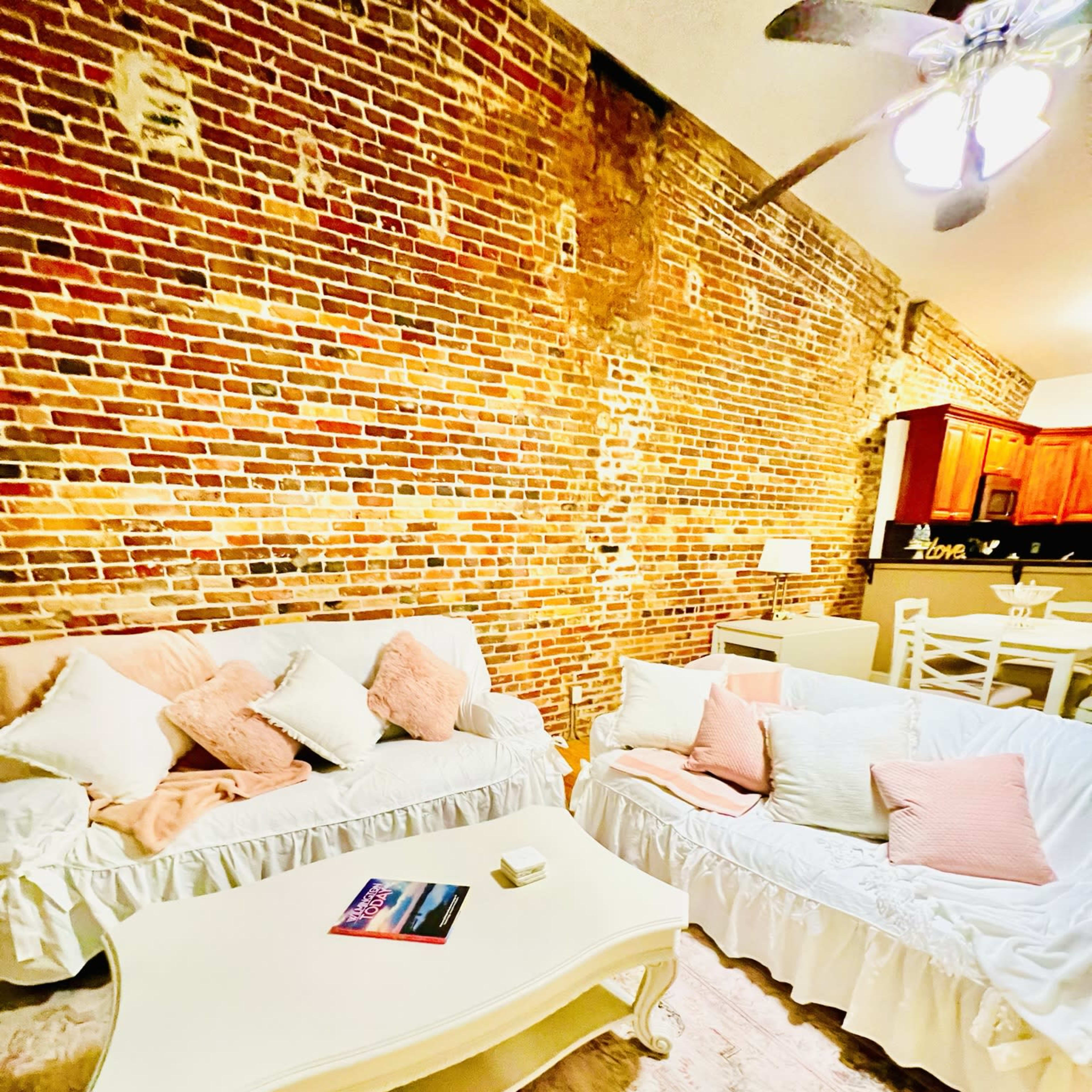 A cozy living space with two sofas, a coffee table, and a brick wall in the background.
