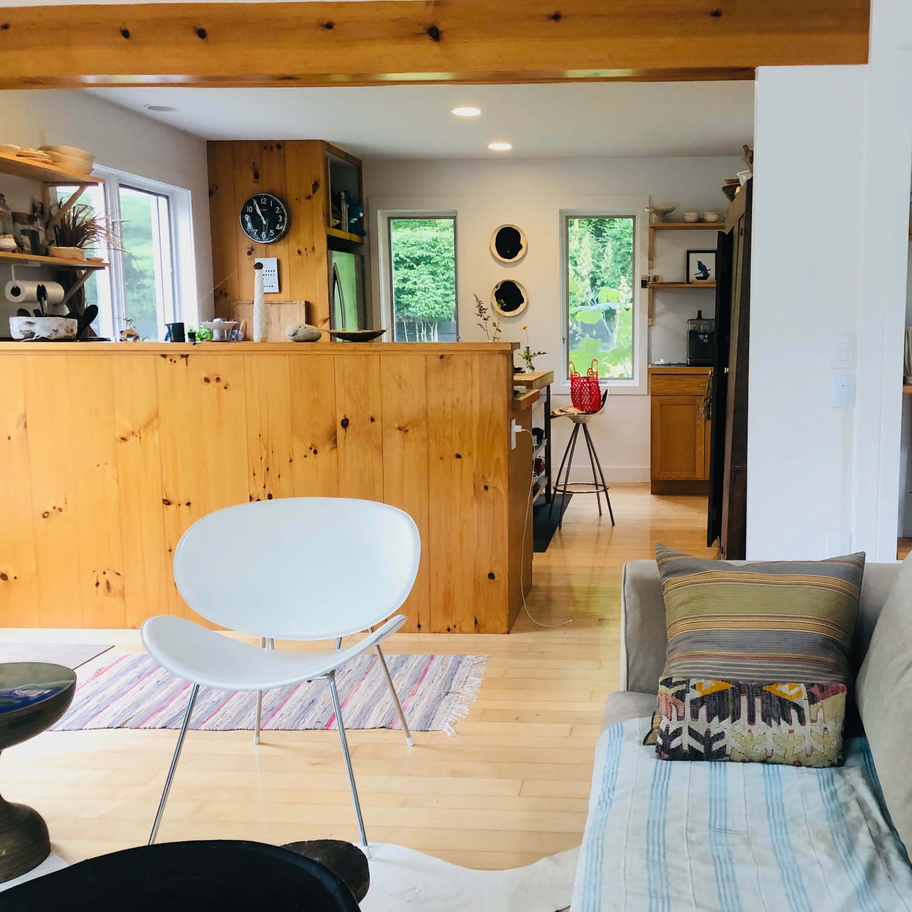 A modern living space features a mix of wooden and white cabinetry, a comfortable sofa, and decorative shelves displaying ceramics and plants.
