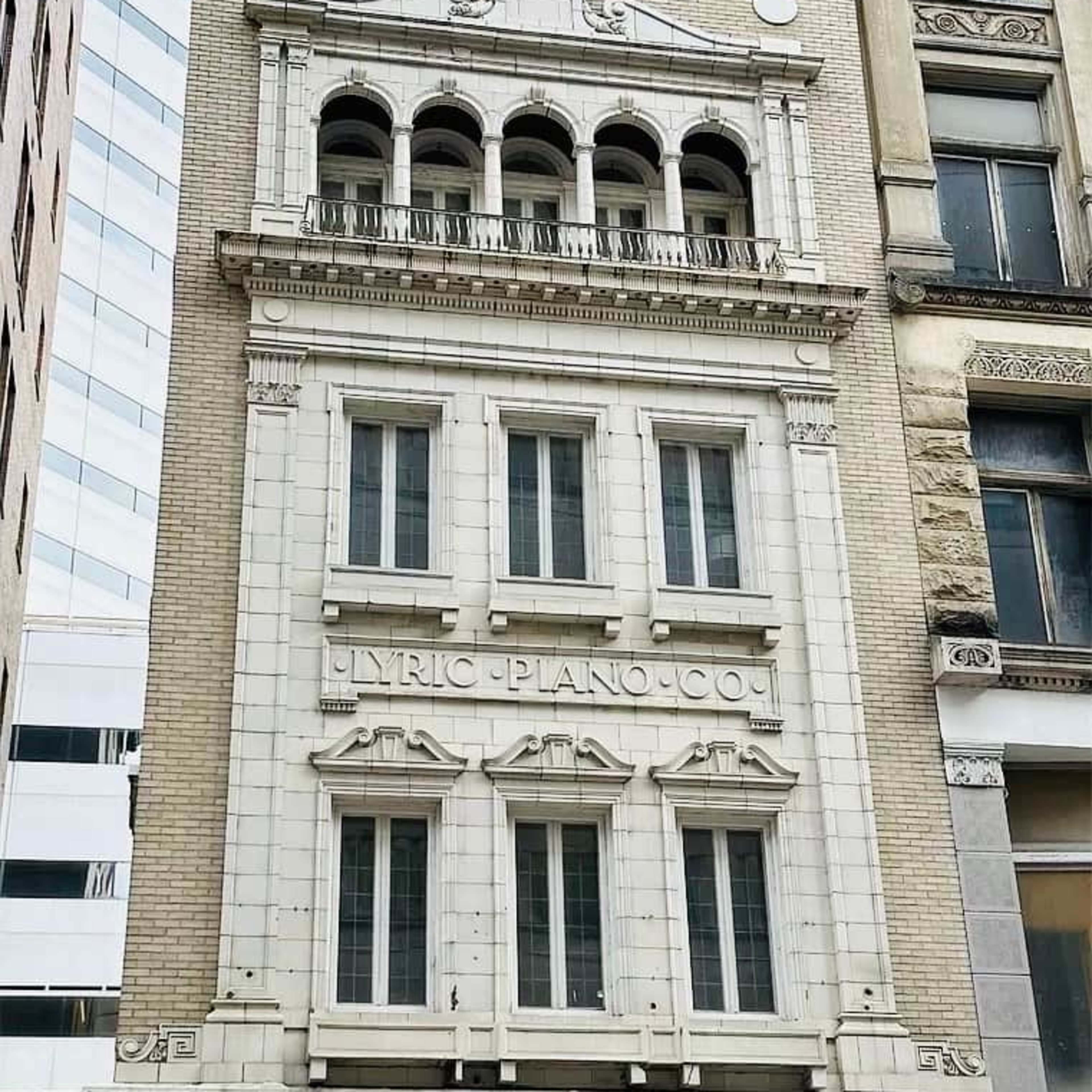 A vintage building with the inscription "LYRIC PIANO CO." prominently displayed above its windows.