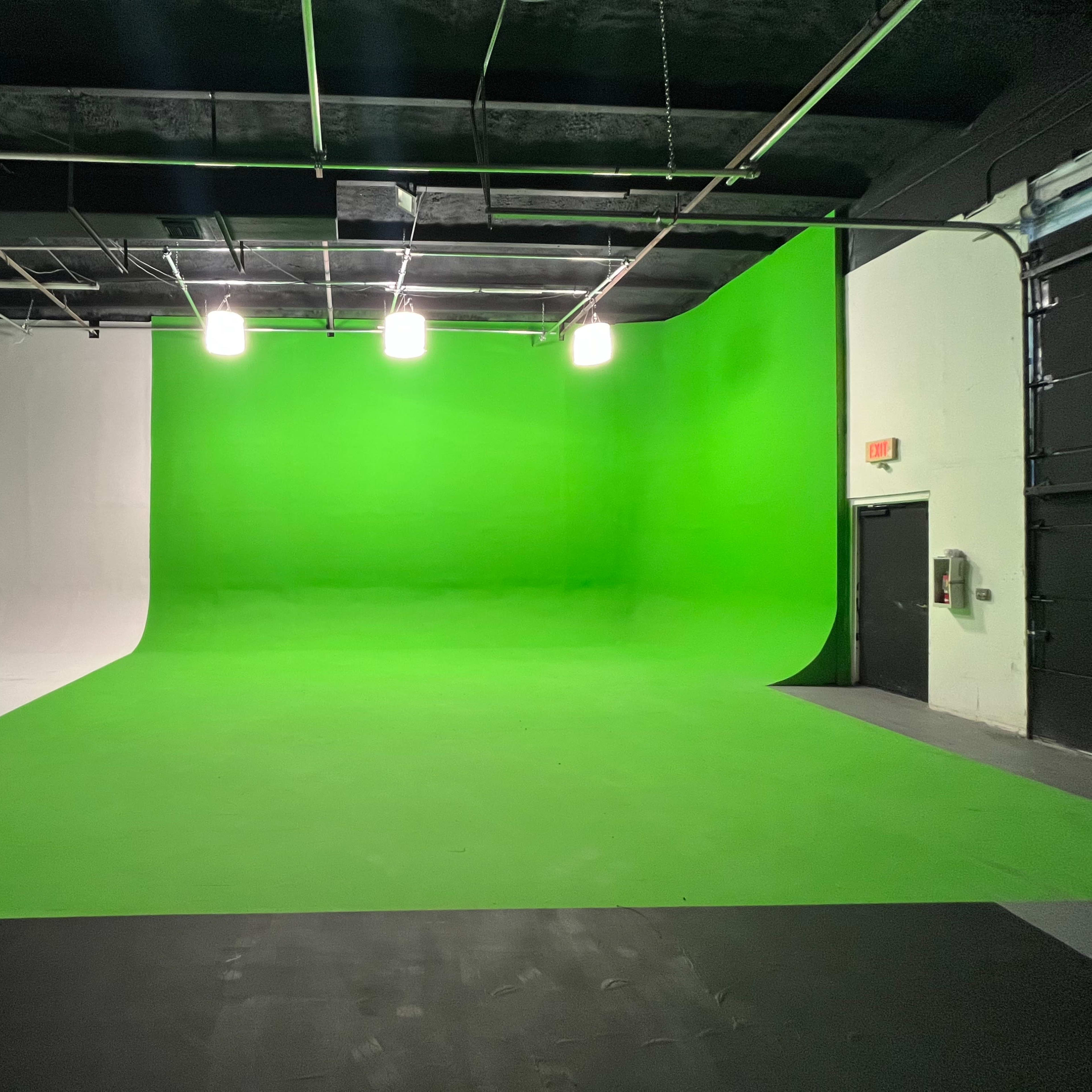 A spacious studio with a green screen backdrop on one side and a white backdrop on the other.