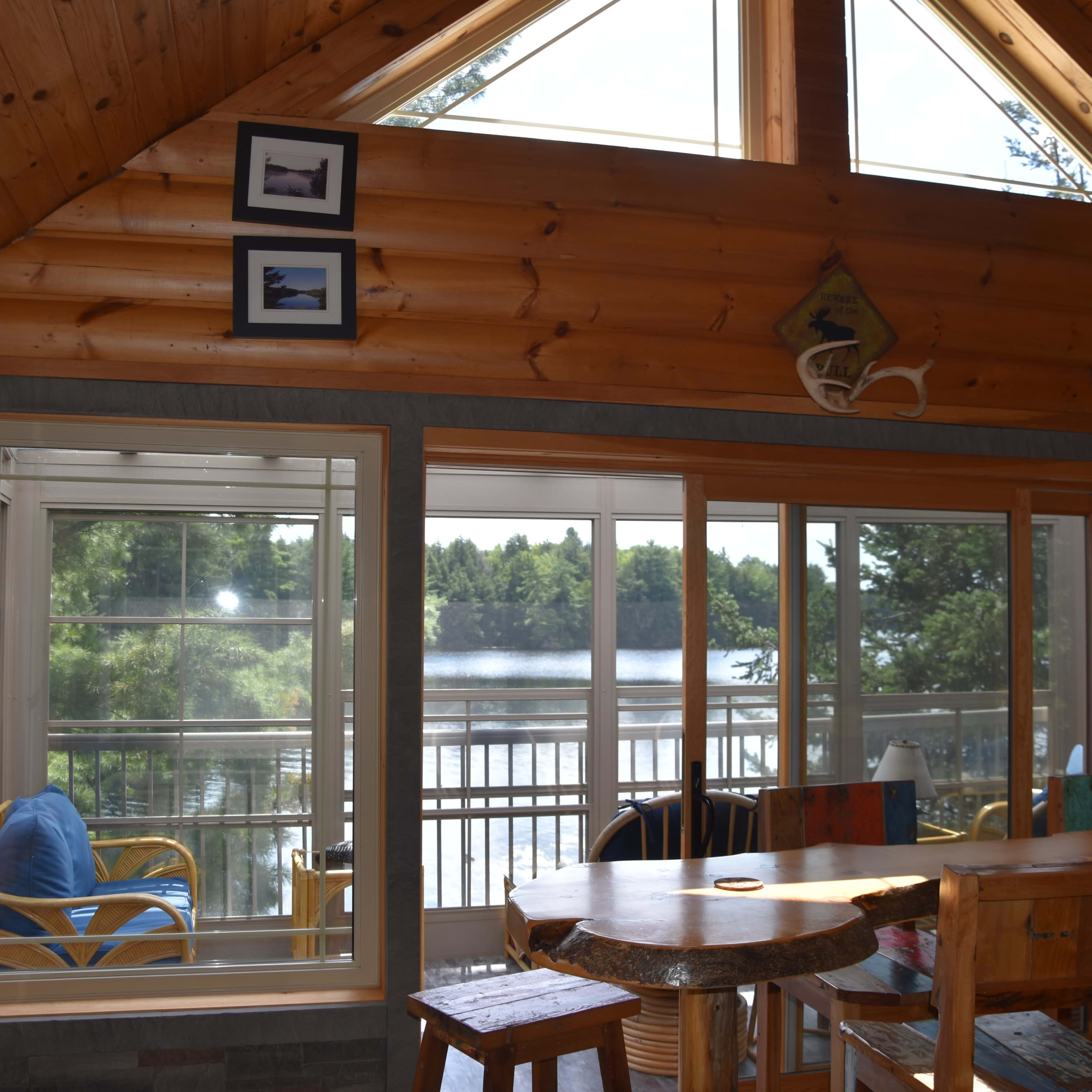 A spacious wooden interior of a cabin featuring large windows that overlook a lake.
