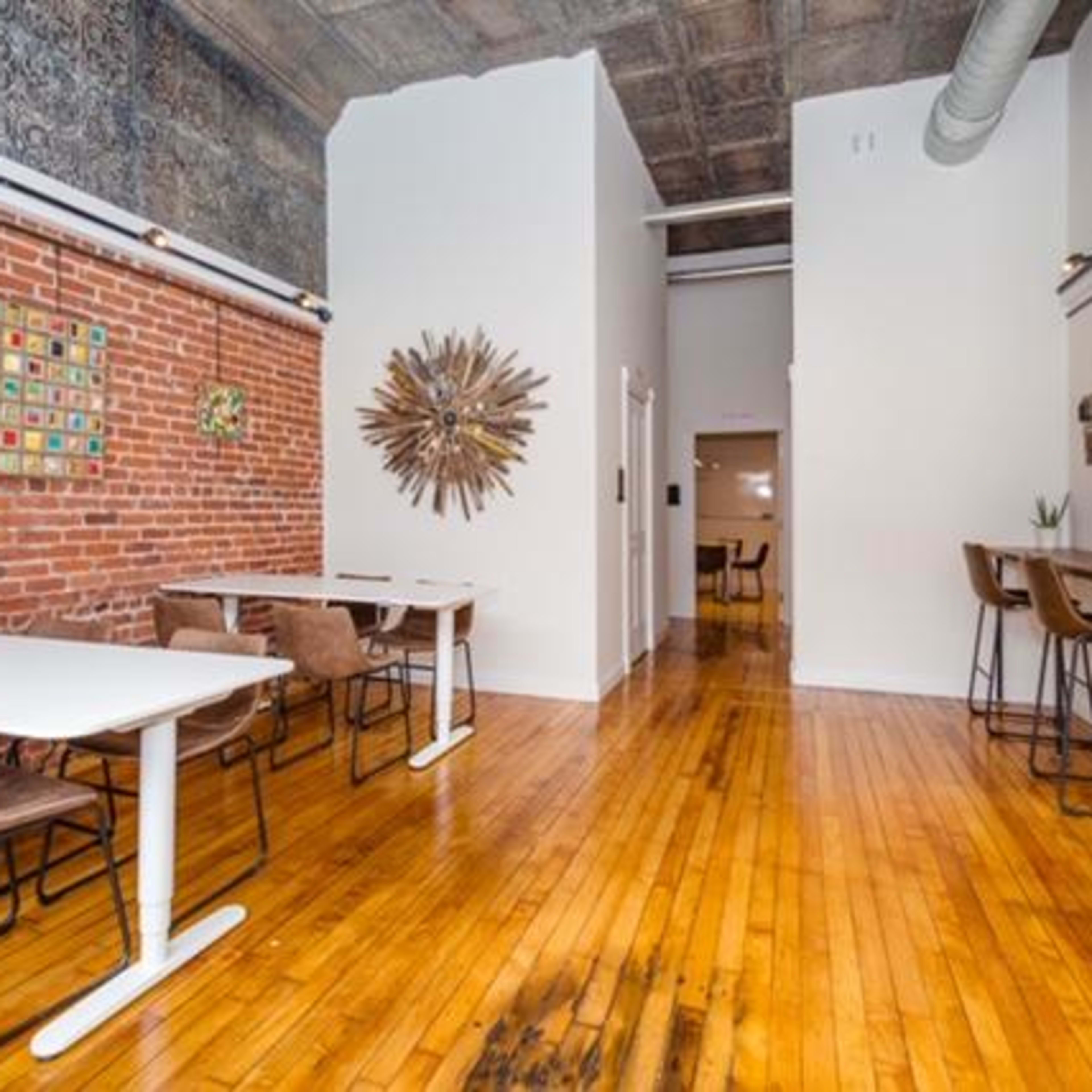 A cozy cafe interior featuring exposed brick walls, wooden floors, and modern tables with chairs.