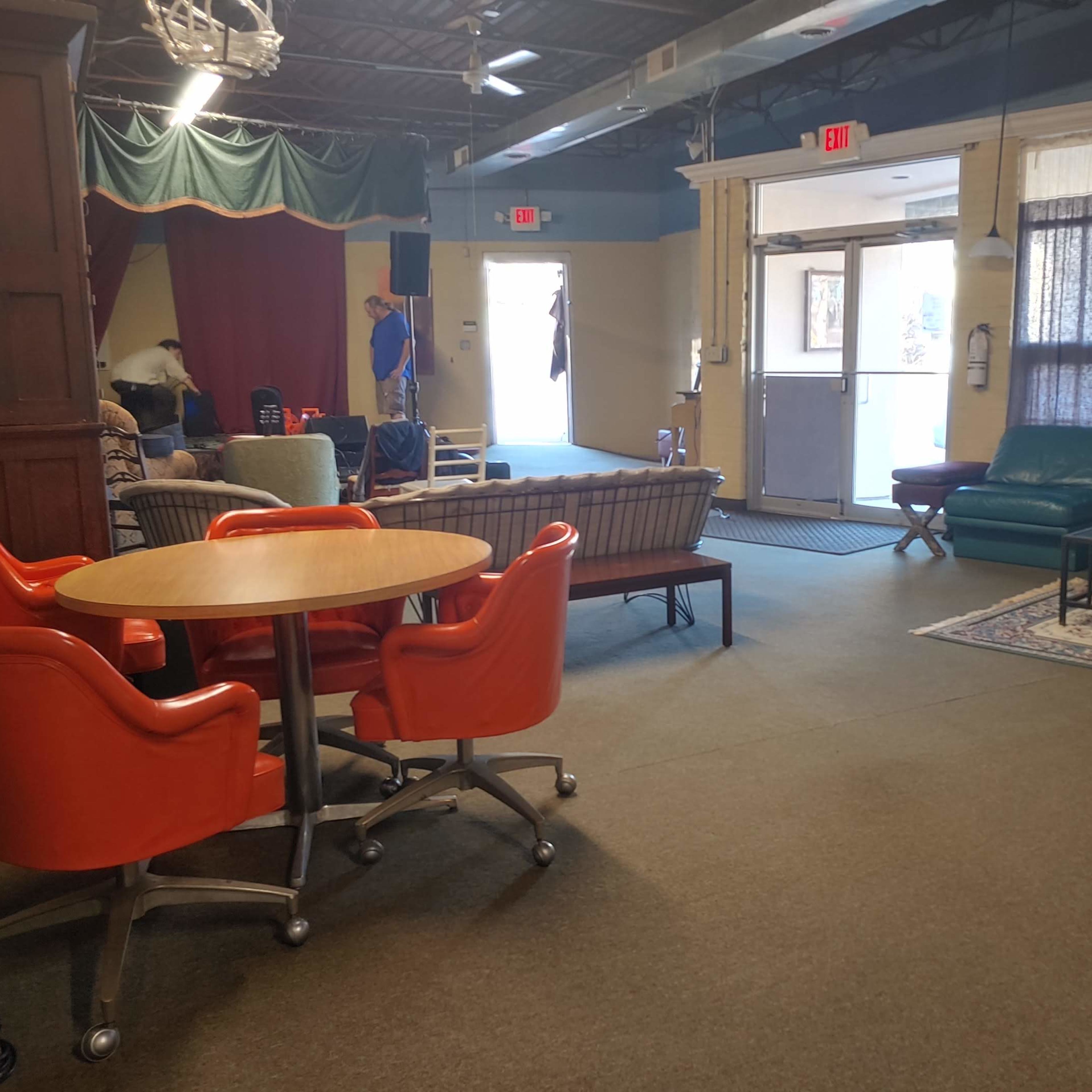 A spacious room divided into two areas featuring various furniture pieces, including sofas, a piano, and a dining table.