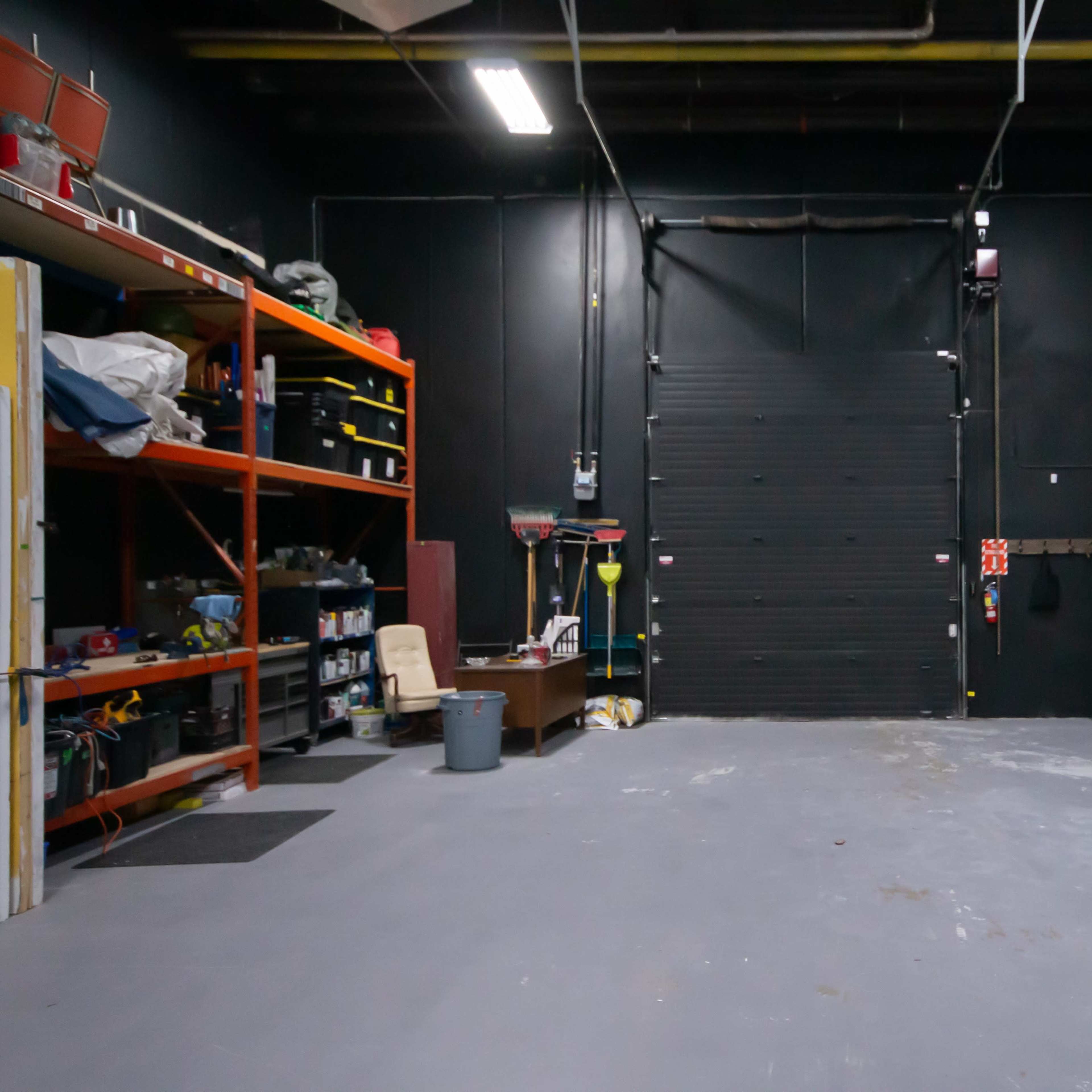 A spacious, dark-colored garage or workshop with shelves filled with various tools and equipment along the walls.