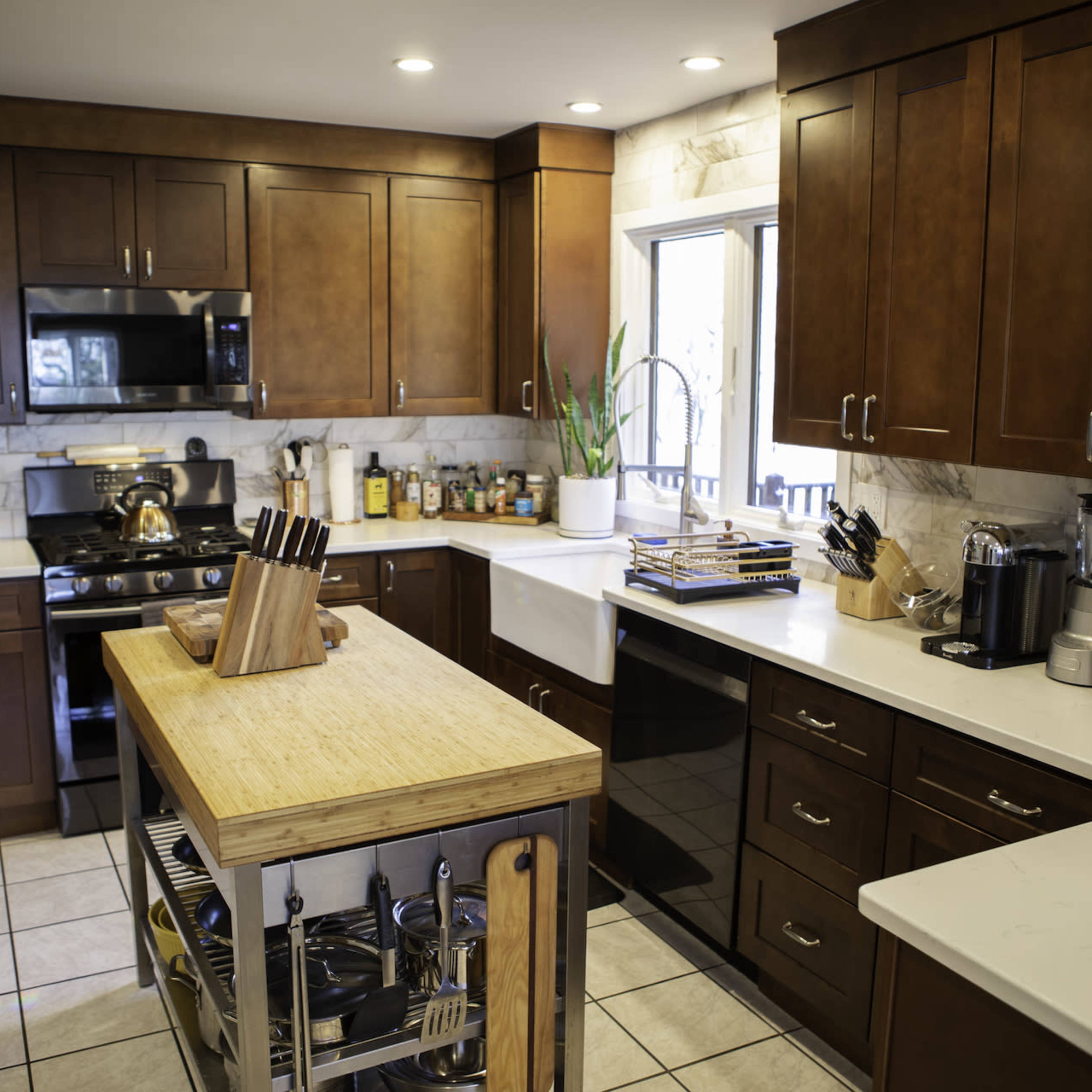 The kitchen features wooden cabinets, stainless steel appliances, and a central island with a wooden top and storage underneath.