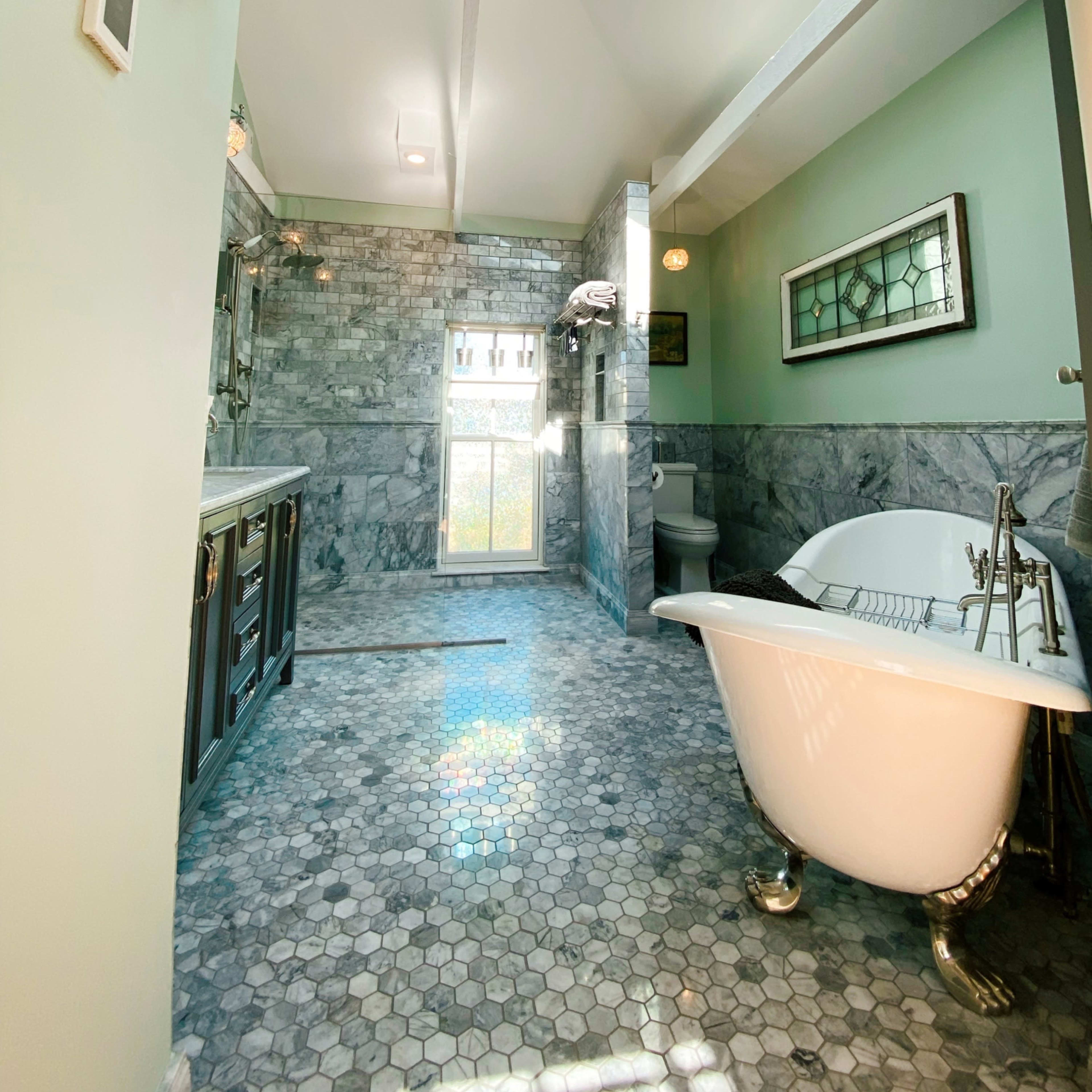 A modern bathroom with a freestanding bathtub, hexagonal tile flooring, and a skylight illuminating the space.