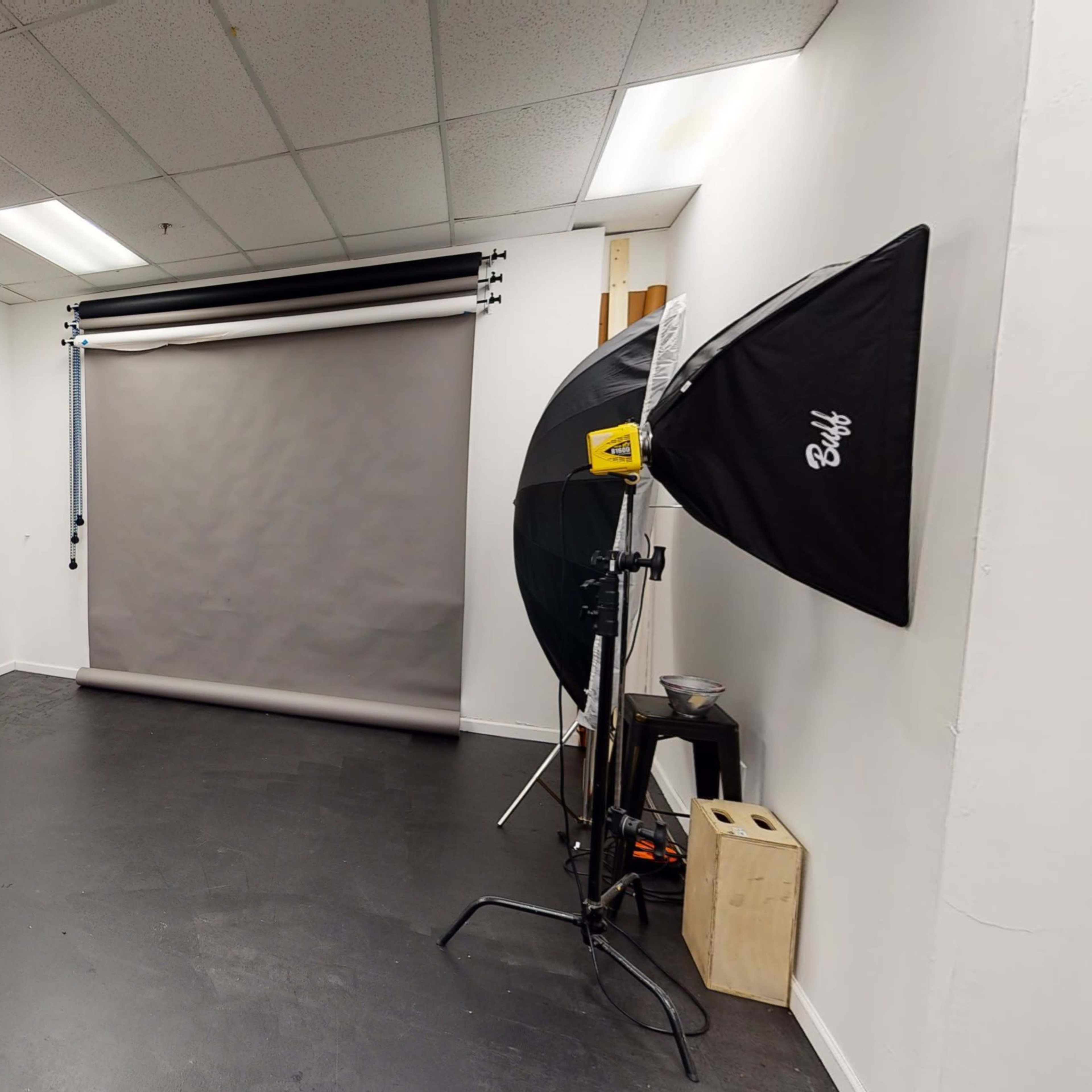A photography studio with a large backdrop, lighting equipment, and a poster on the wall.