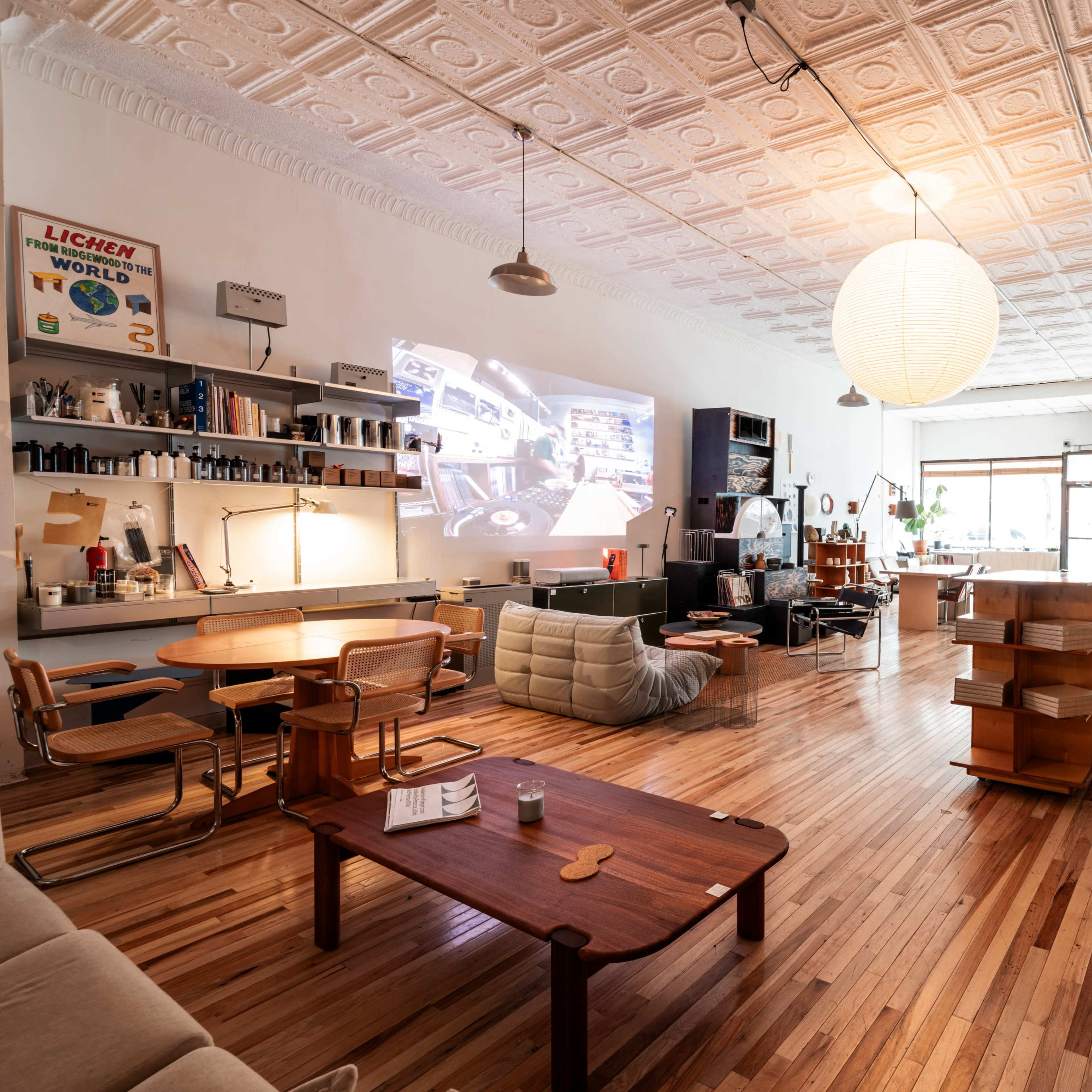 The spacious room features wooden flooring, contemporary furniture, and a large projection screen on one wall.