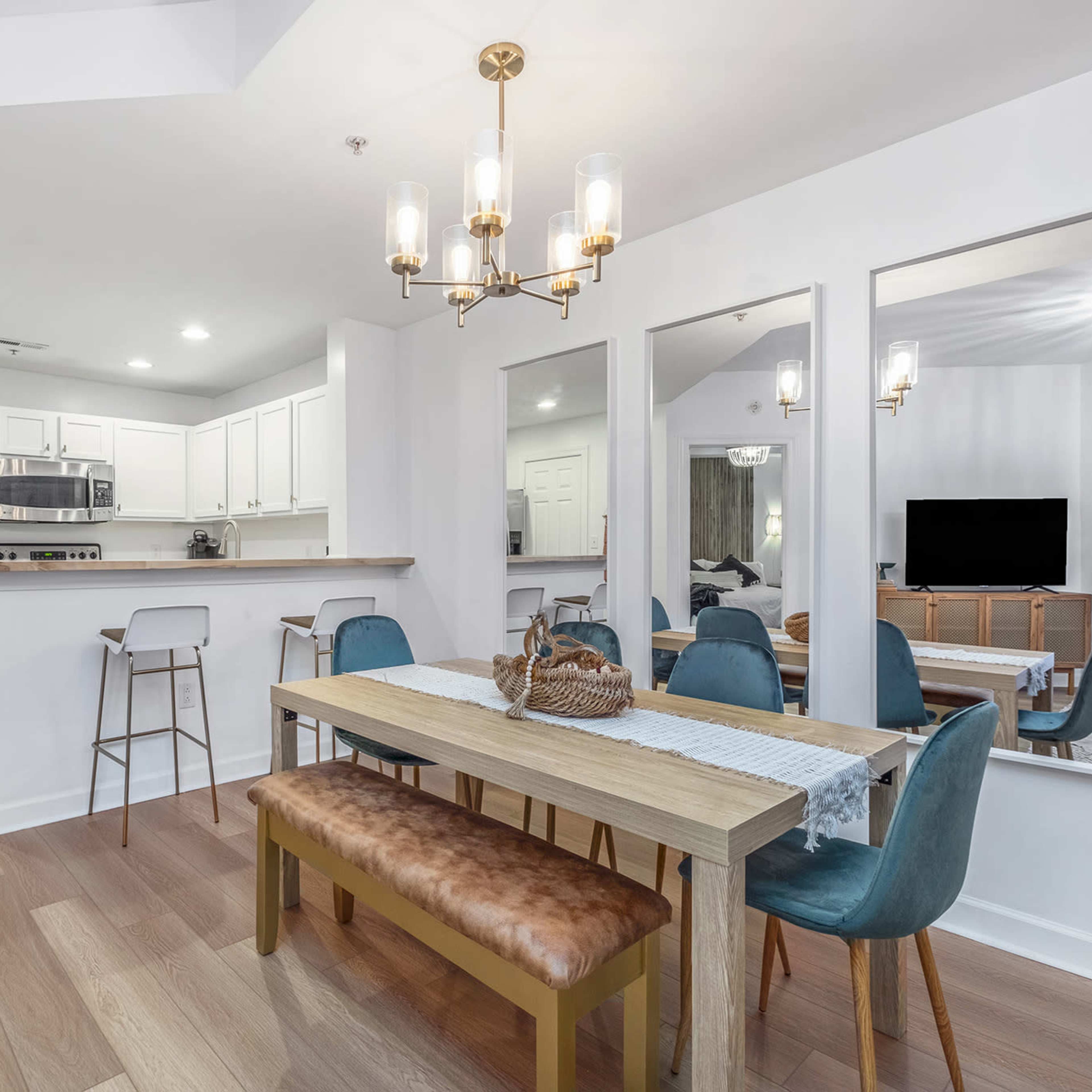 A modern dining area with a wooden table, blue chairs, and an open kitchen in the background.